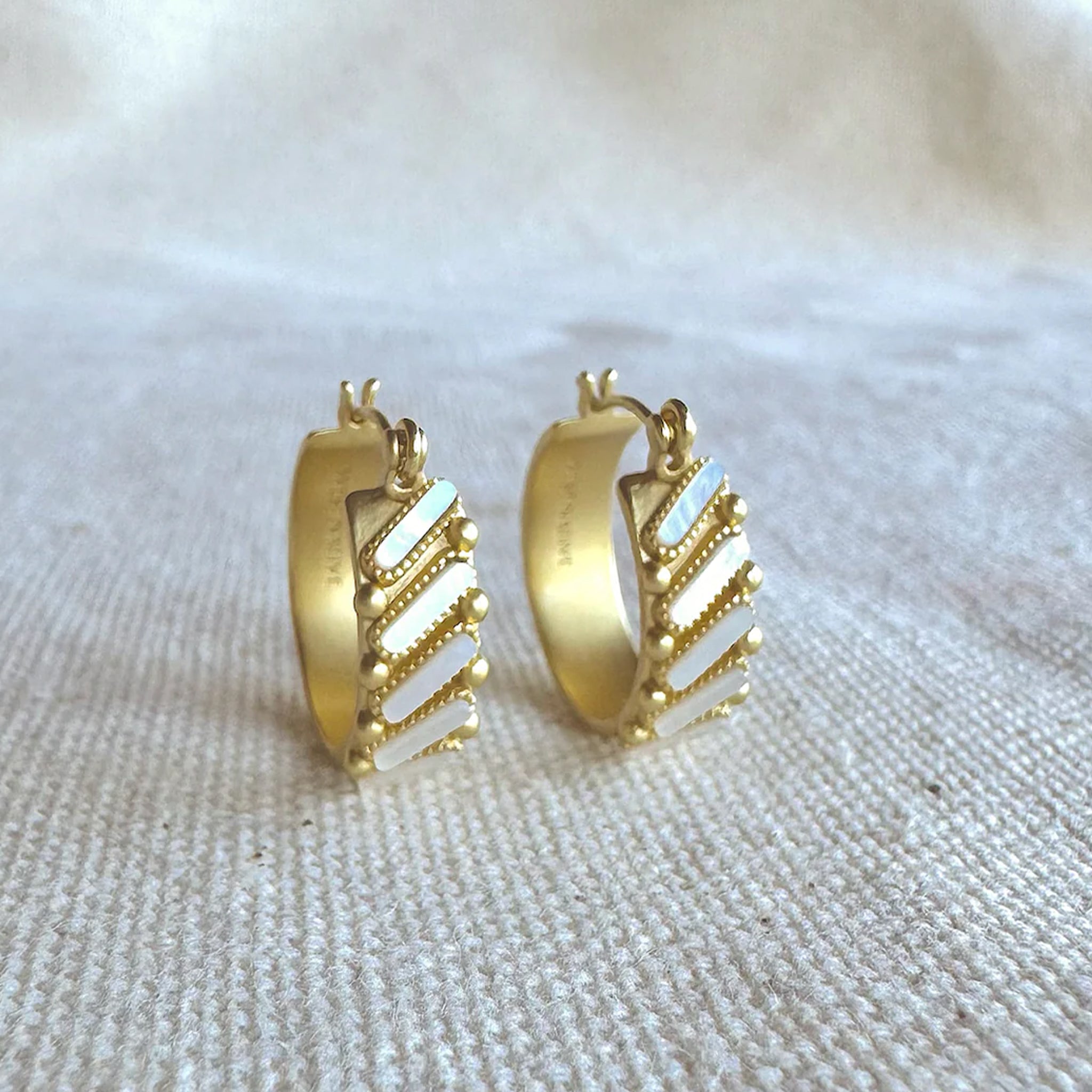 A gold pair of earrings with mother of pearl. 