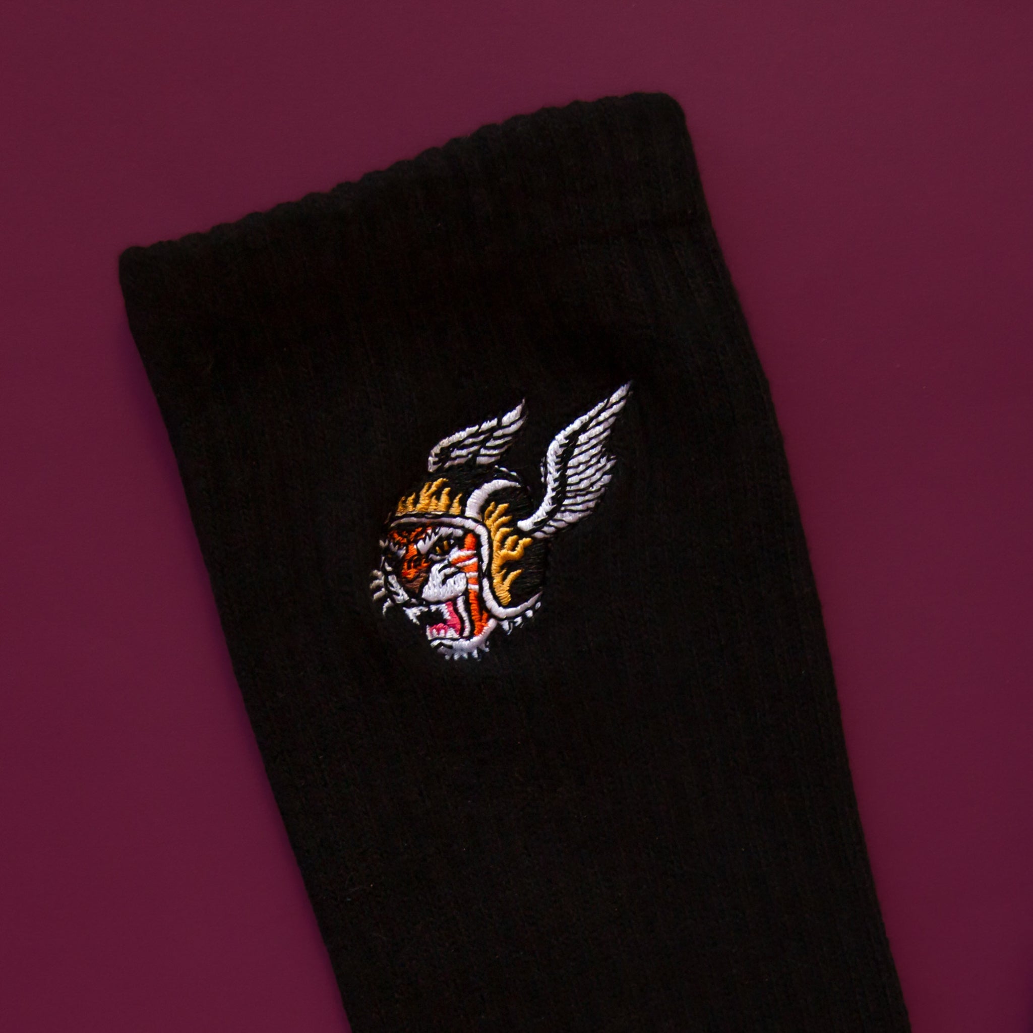 A black pair of crew socks with a tiger with a wing helmet graphic on the side. 