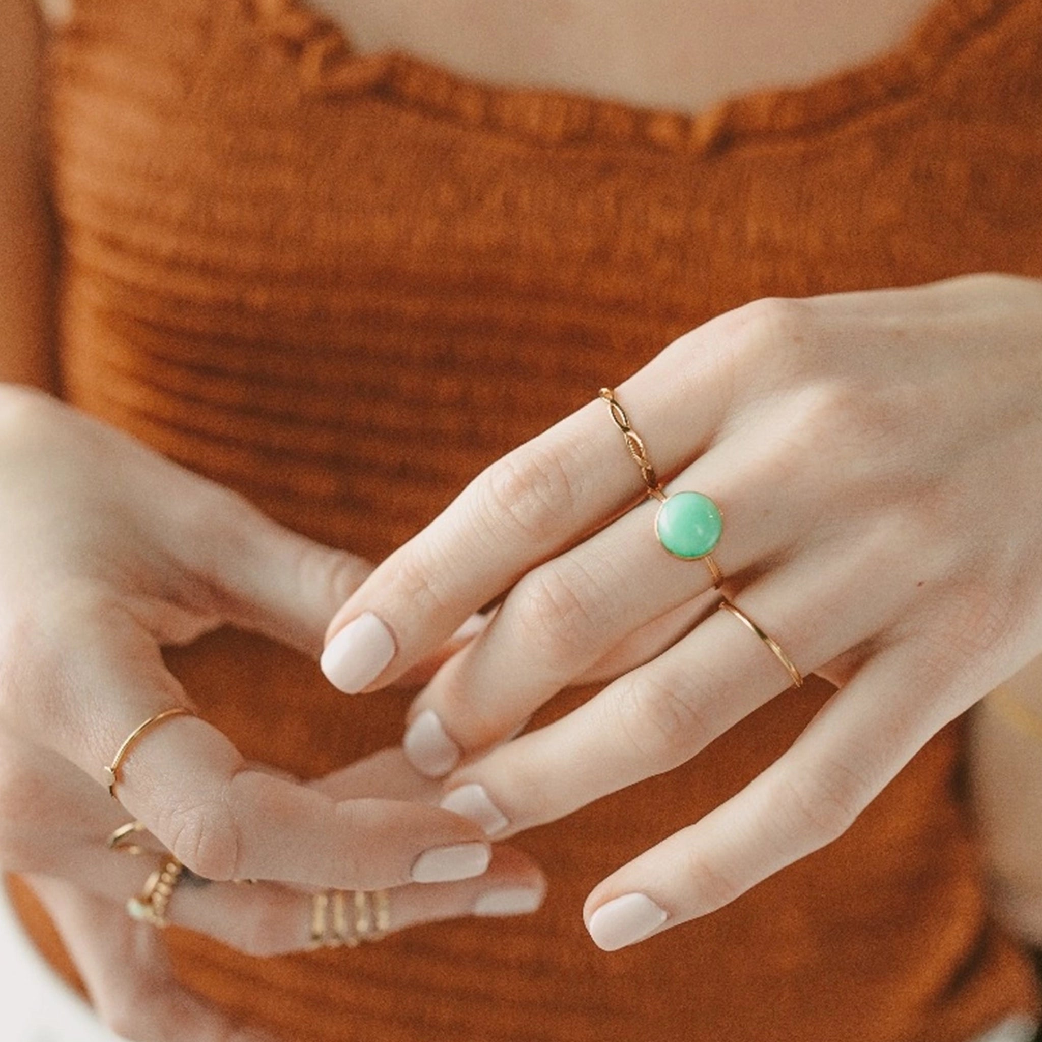 A thin gold ring with a green chrysoprase stone in the center.