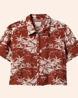 A rust colored button up short sleeve shirt with an ivory tropical print.