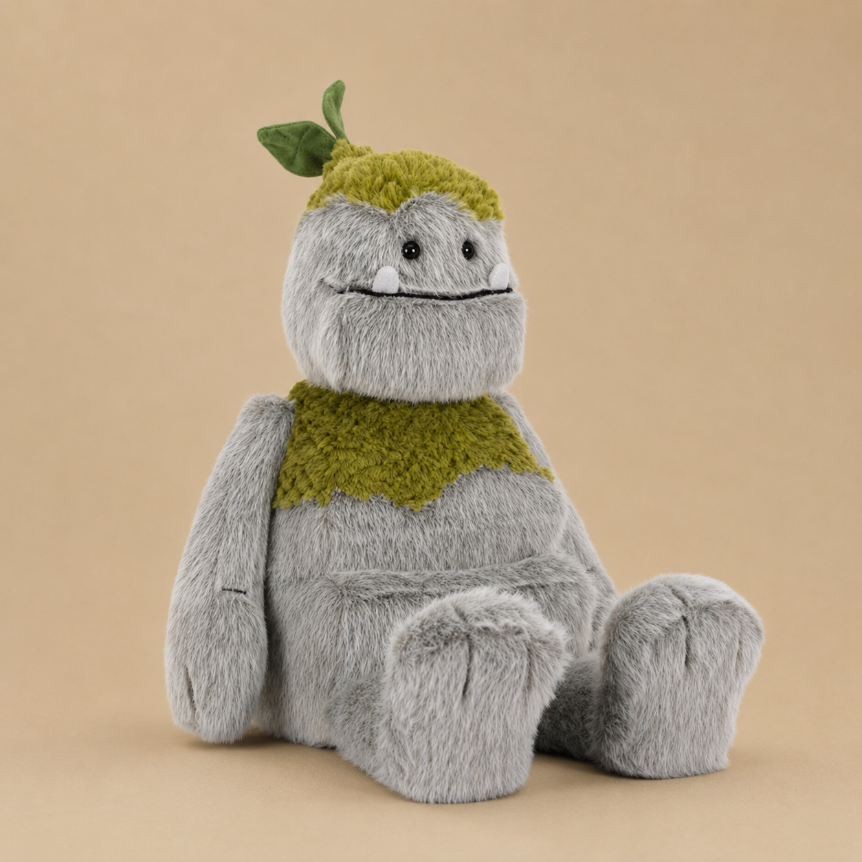 Soft plush forest creature with fuzzy gray fur, moss-green accents, a sweet smile, and a tiny leaf on its head.