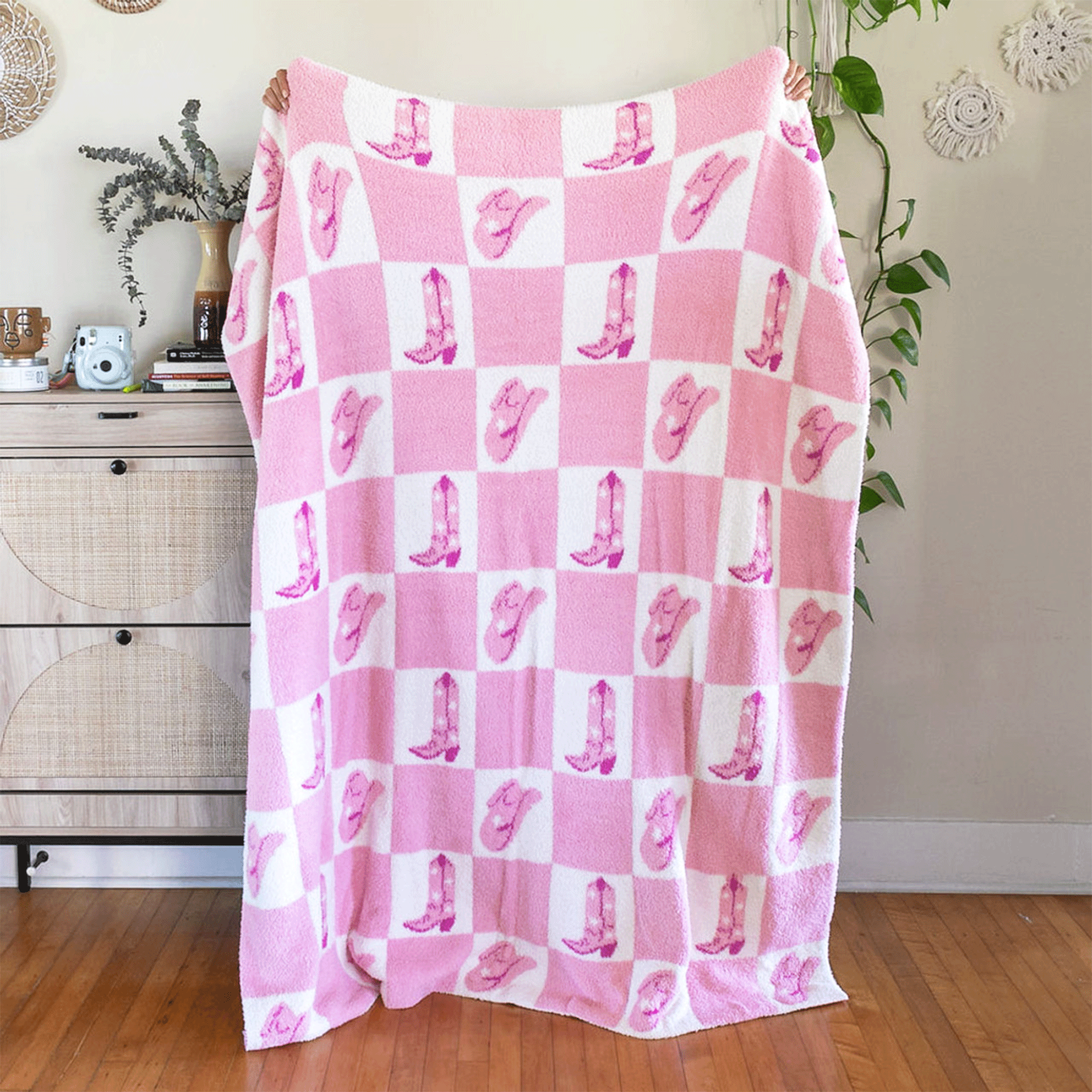 A full length view of the pink and white checkered blanket with alternating pink cowgirl hats and cowgirl boots in each white square.