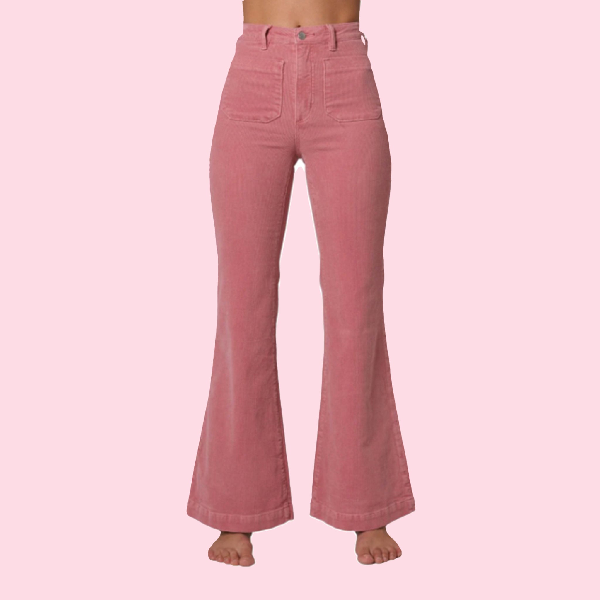 On a pink background is a model wearing the pink corduroy pants with front pockets and a flare bottom. 