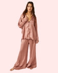 A model wearing an oversized slouchy fit pajama set in a rose gold color. 