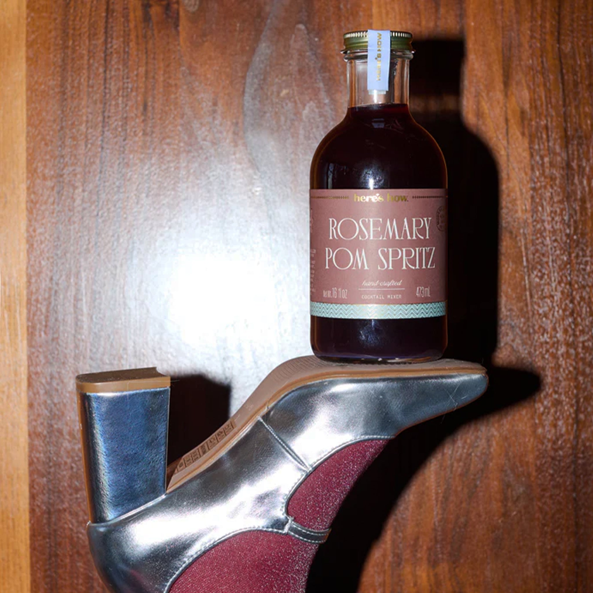 A bottle of cocktail mix with a label that reads, 'Rosemary Pom Spritz'. 