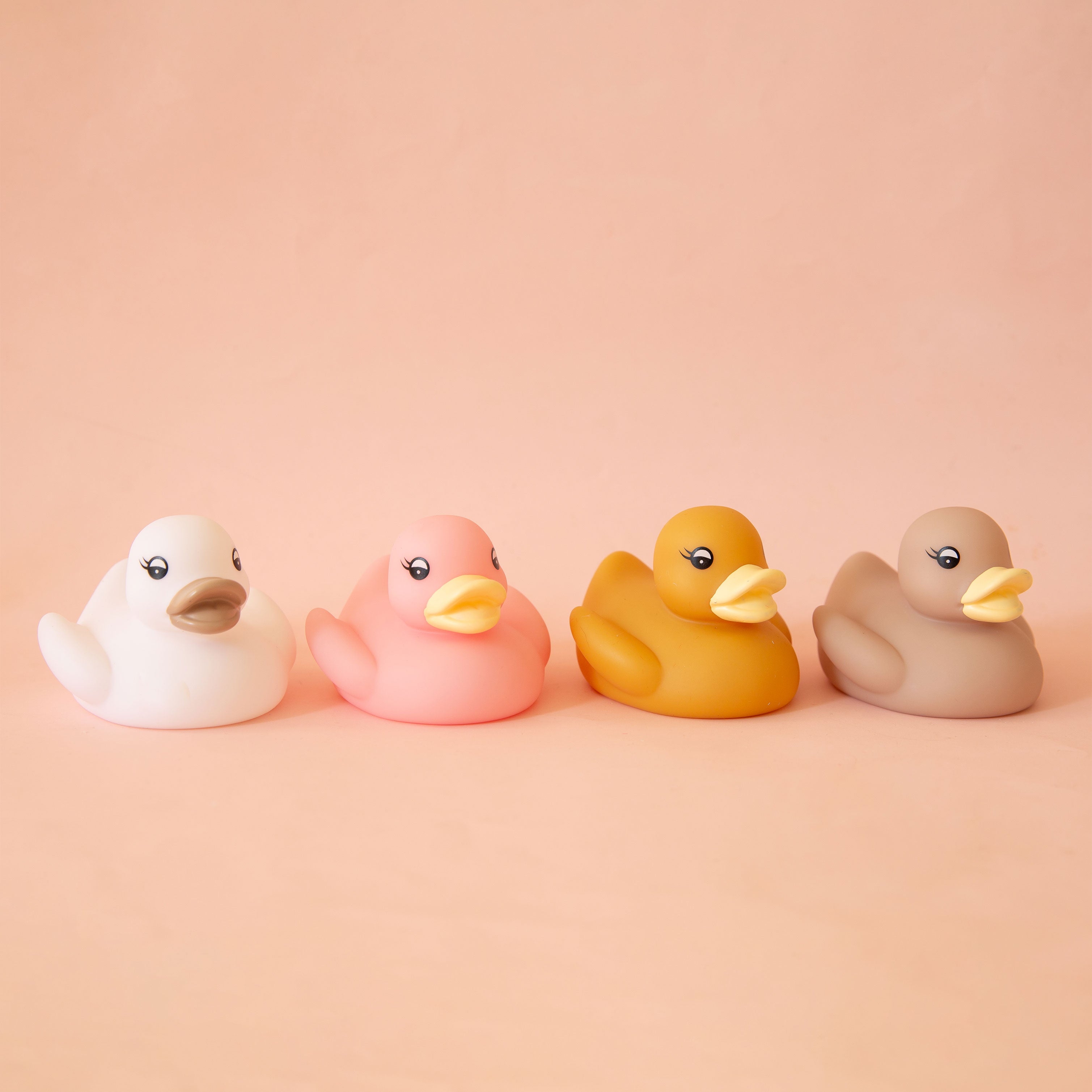 On a peach background is a set of four bath time ducks. 