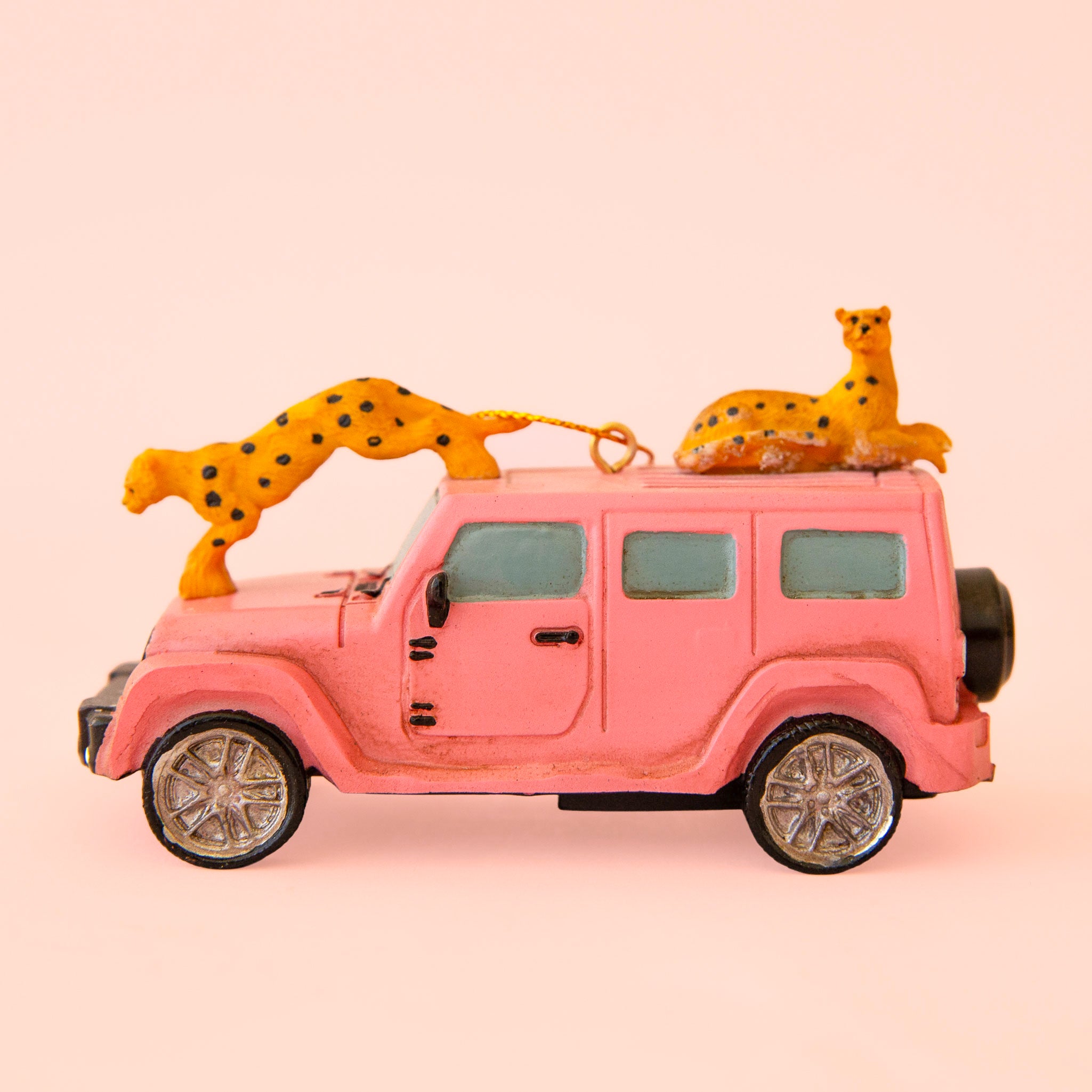 Bright pink safari car ornament with two cheetahs perched on the hood and roof of the car. 