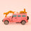 Bright pink safari car ornament with two cheetahs perched on the hood and roof of the car. 