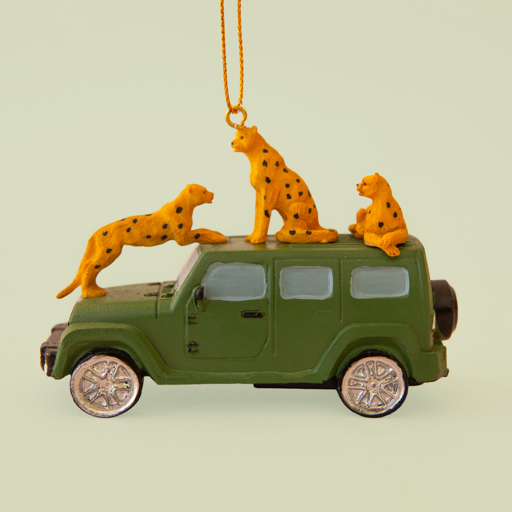 Dark green safari car ornament with three cheetahs perched on the hood and roof of the car. 