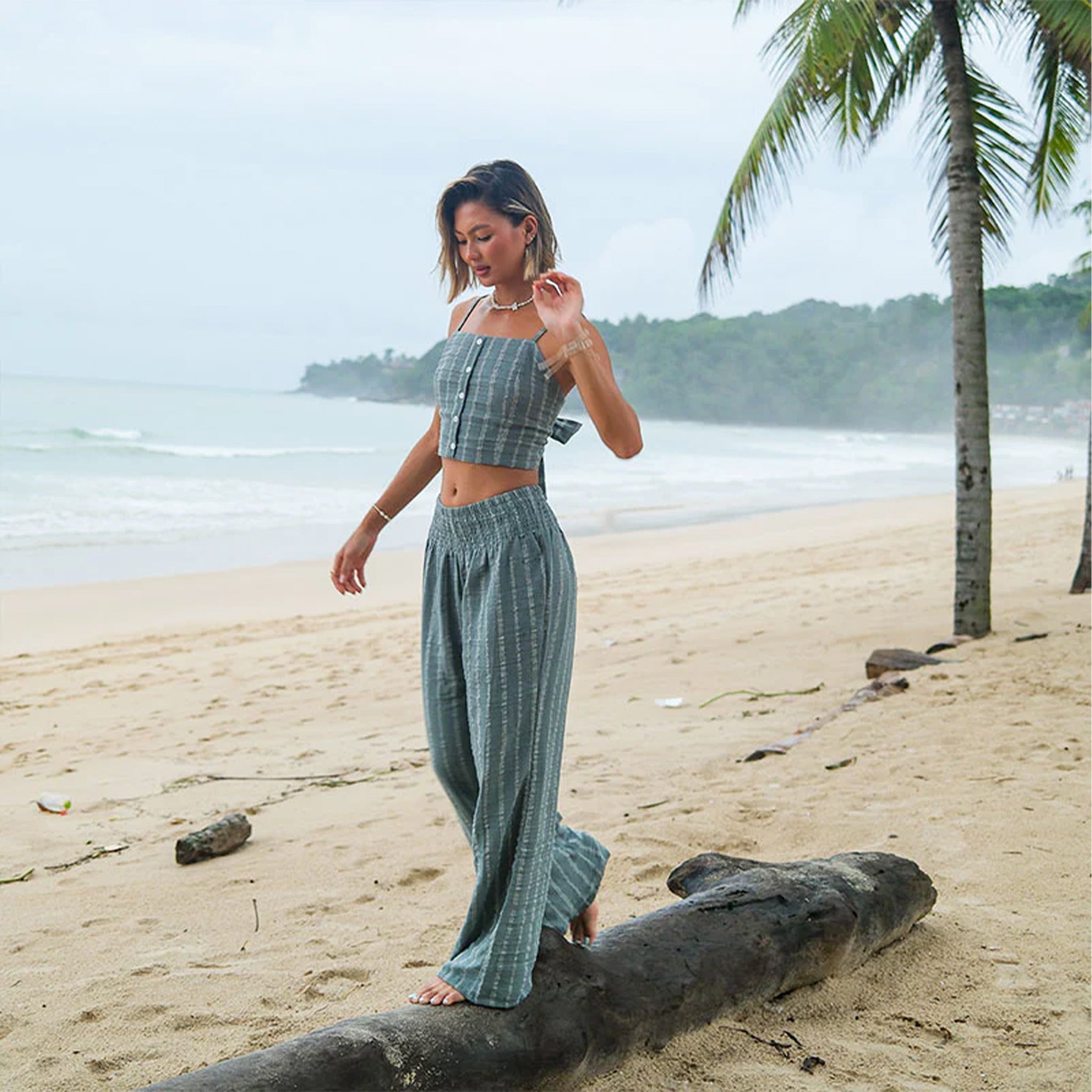A model wearing a pair of sage striped pants. 