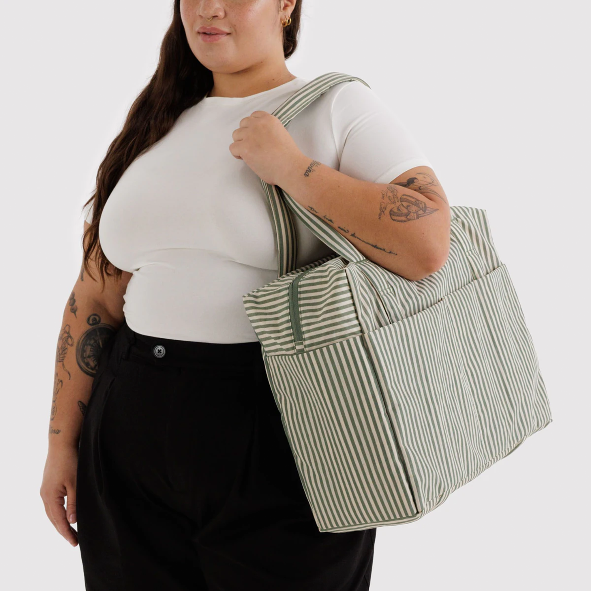 sage colored striped bag on a model's shoulder.