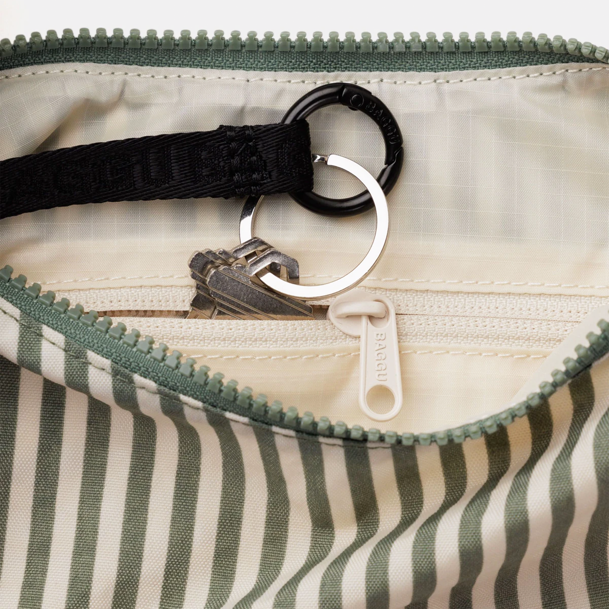 The interior of a nylon striped bag showing keys in a zippered pocket.
