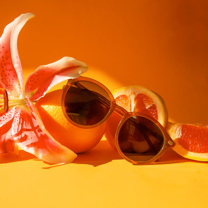 A thin rounded burnt orange / brown framed sunglass with a grey lens.