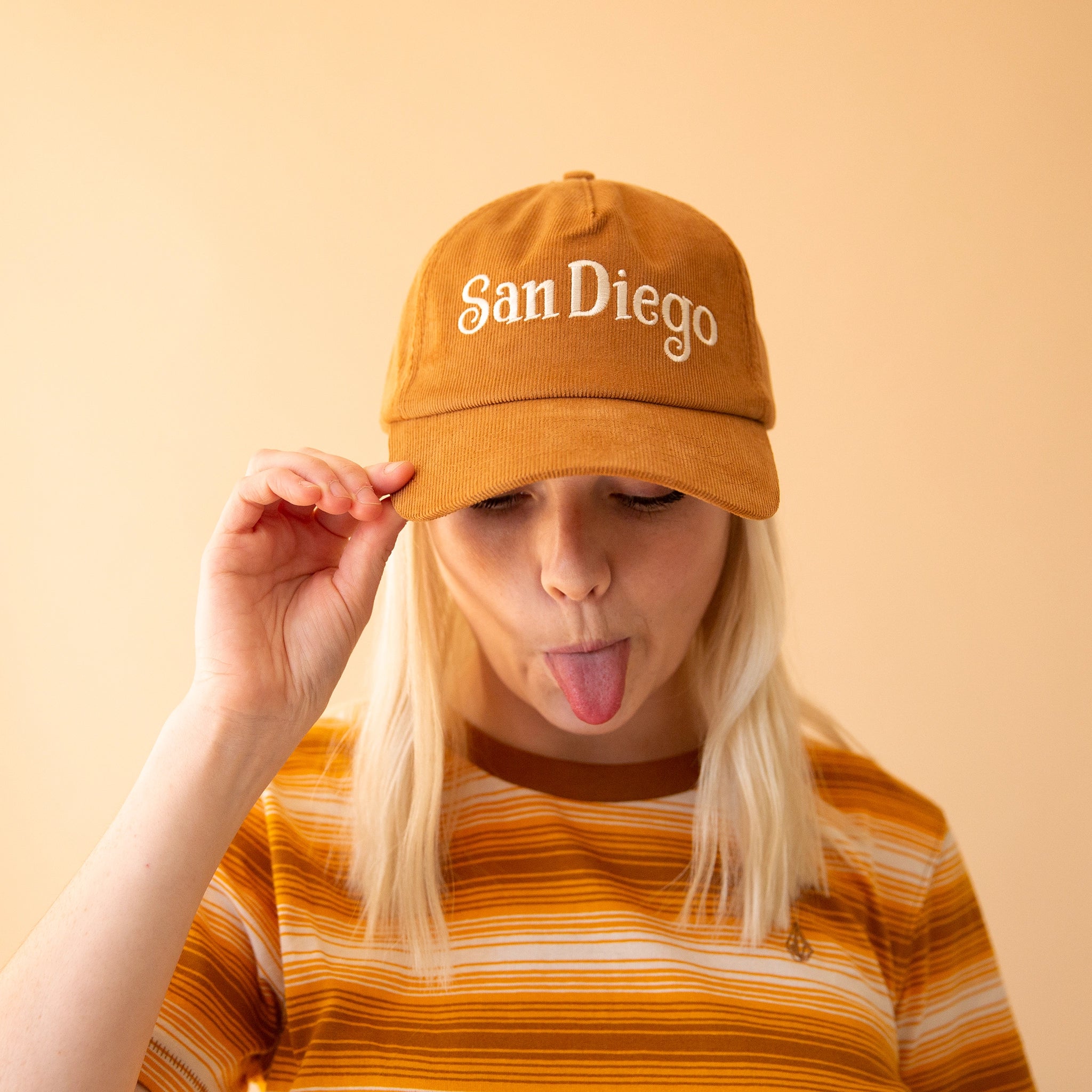 A model wearing the toffee colored baseball cap that has a corduroy texture and says, &quot;San Diego&quot; in white lettering. 