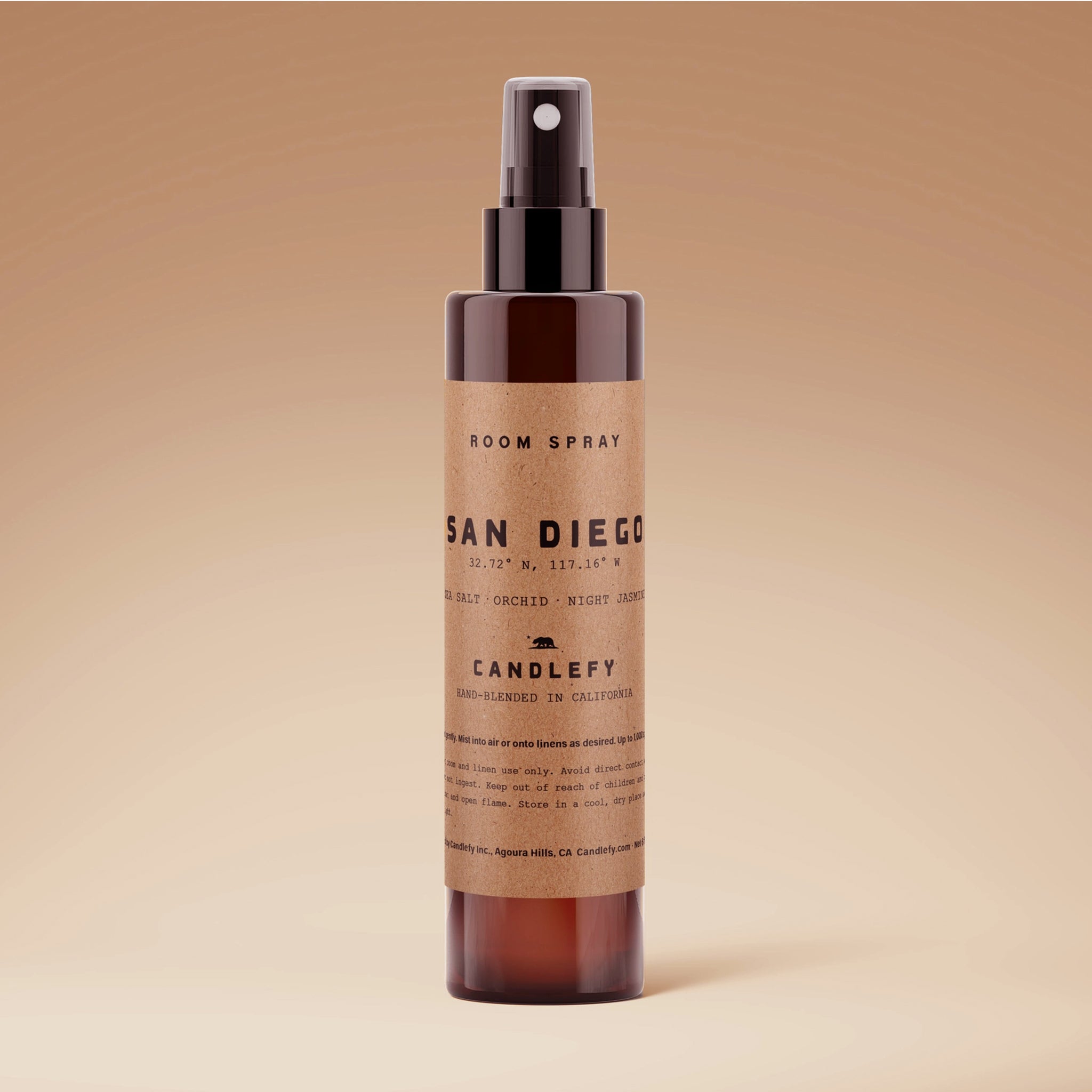 A amber glass bottle of room spray with black details and text that reads, 'San Diego'. 