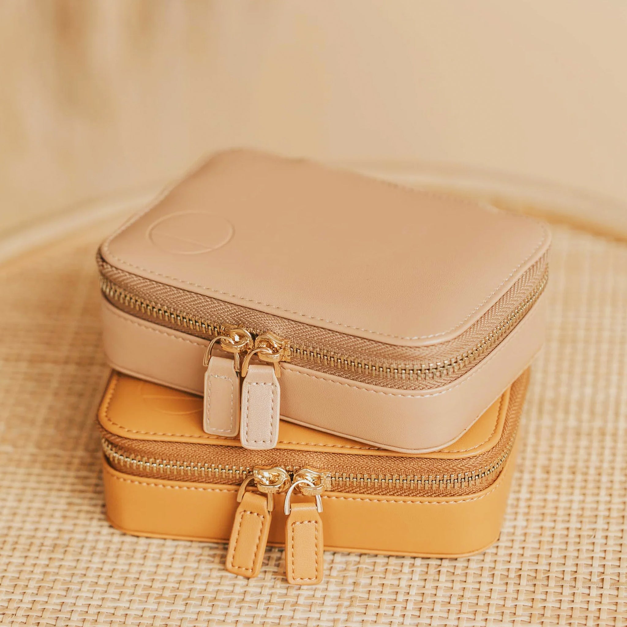 The sand travel jewelry case with a double zipper on top of a different colored case.  