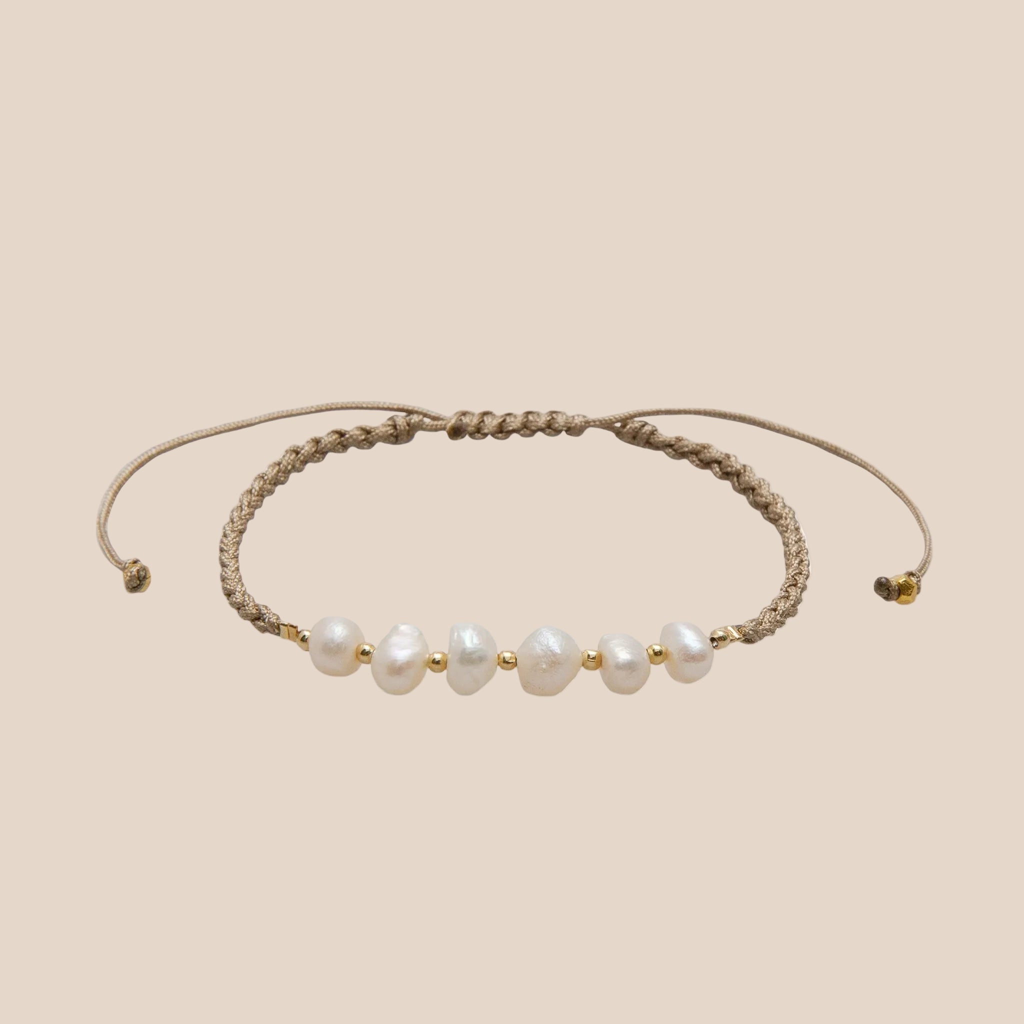 A tan woven rope bracelet with pearl beads int he center. 