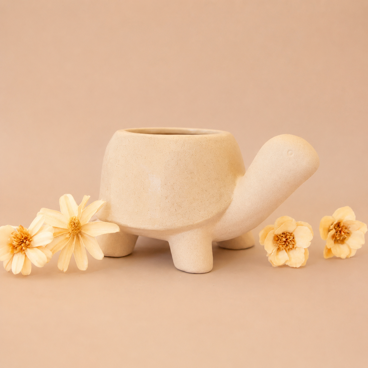 a ceramic planter in the shape of a turtle with a light tan "shell" with a subtle speckle detail.