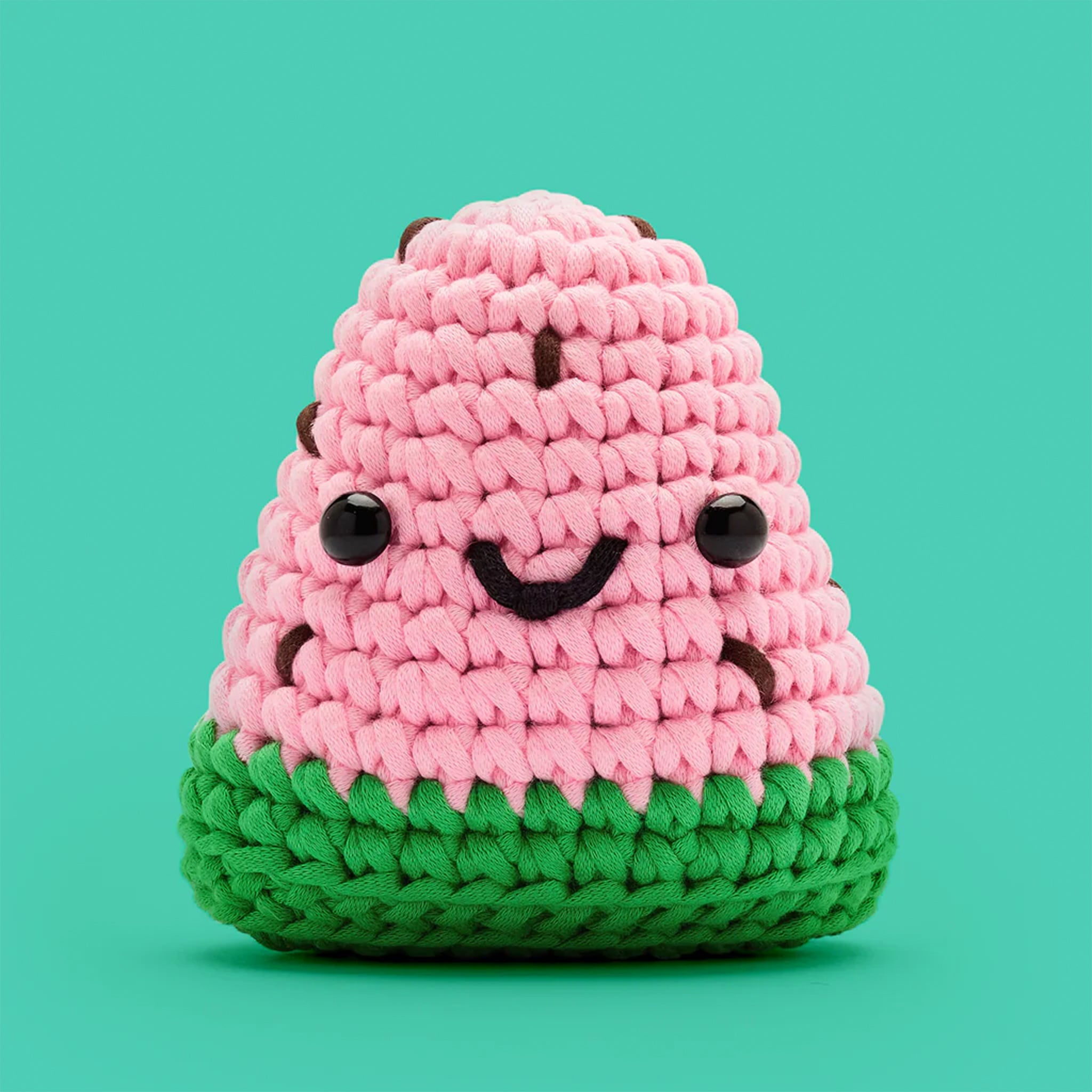 A crochet kit that makes a pink and green watermelon with a smiling face. 
