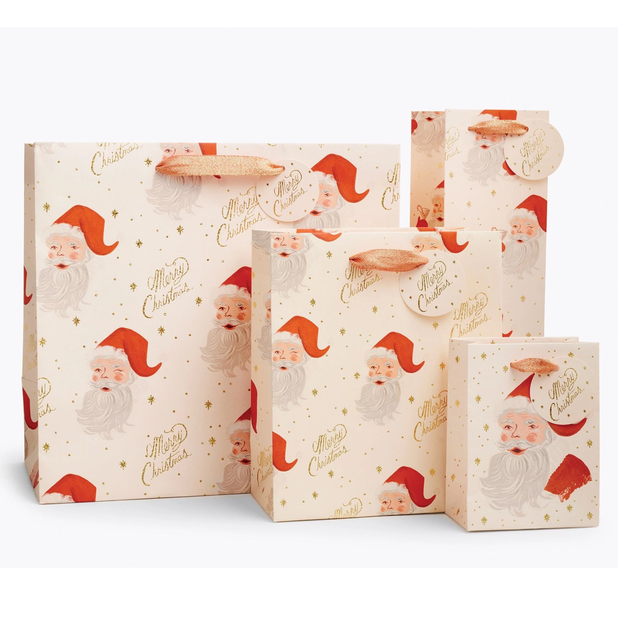 On a tan background is three different sized ivory gift bags with a red Santa design along with gold text that reads, "Merry Christmas".