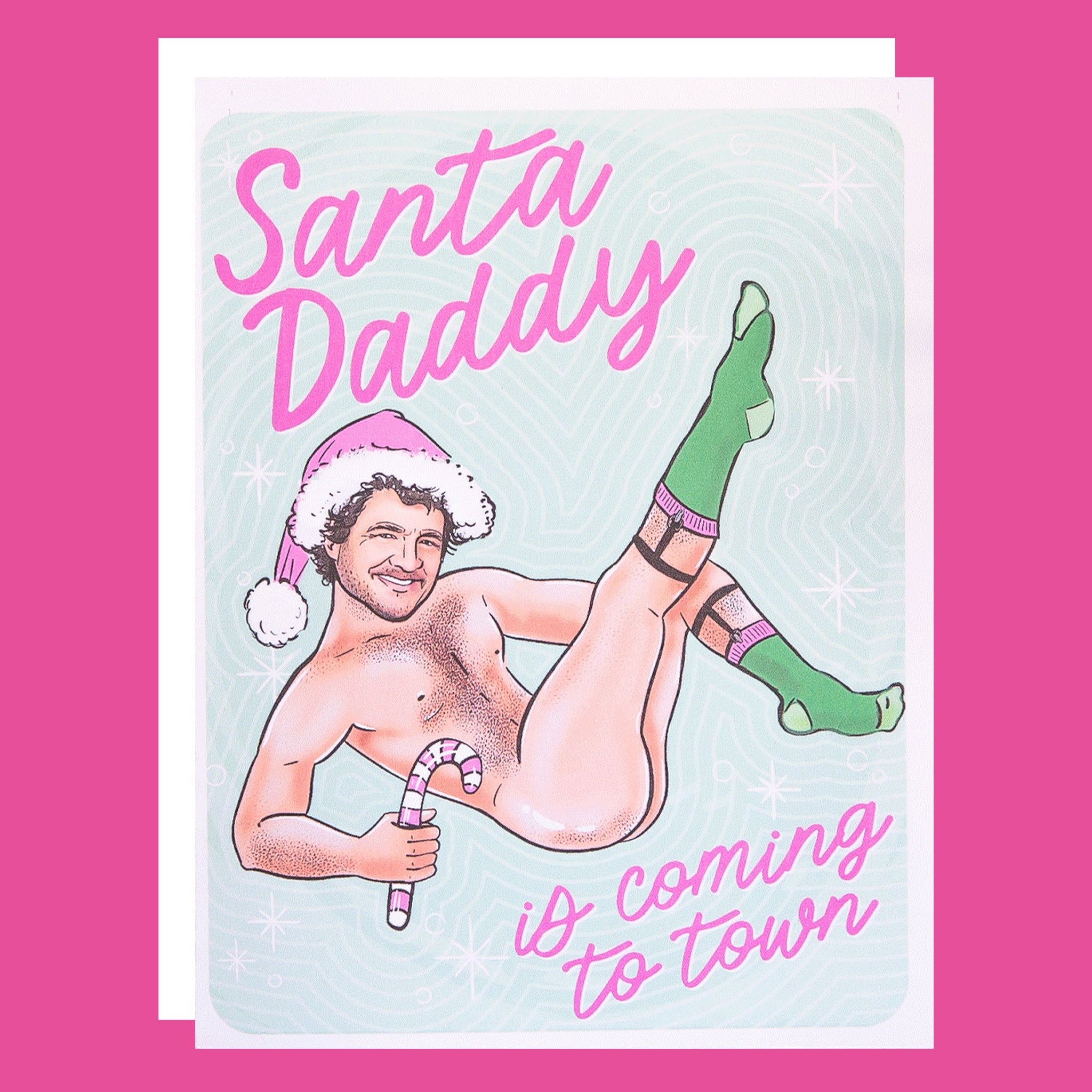 green and white card with an image of Pedro Pascal with a pink Santa hat on and pink text that reads, "Santa Daddy Is Coming To Town".