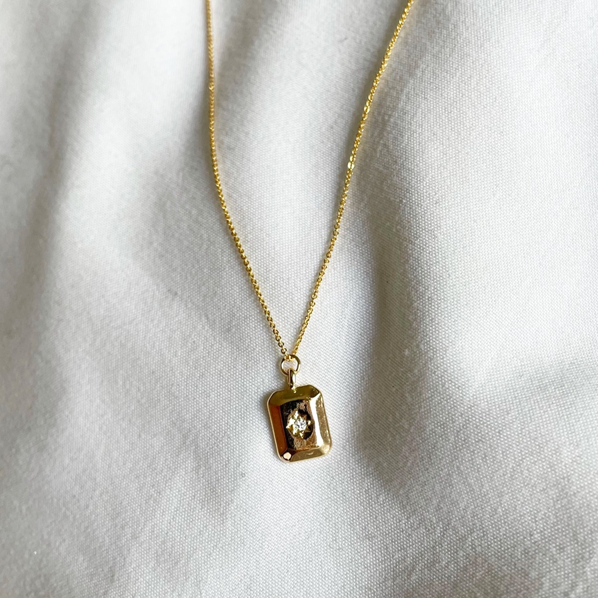 A gold rectangle pendant necklace with a cz stone in the center. 