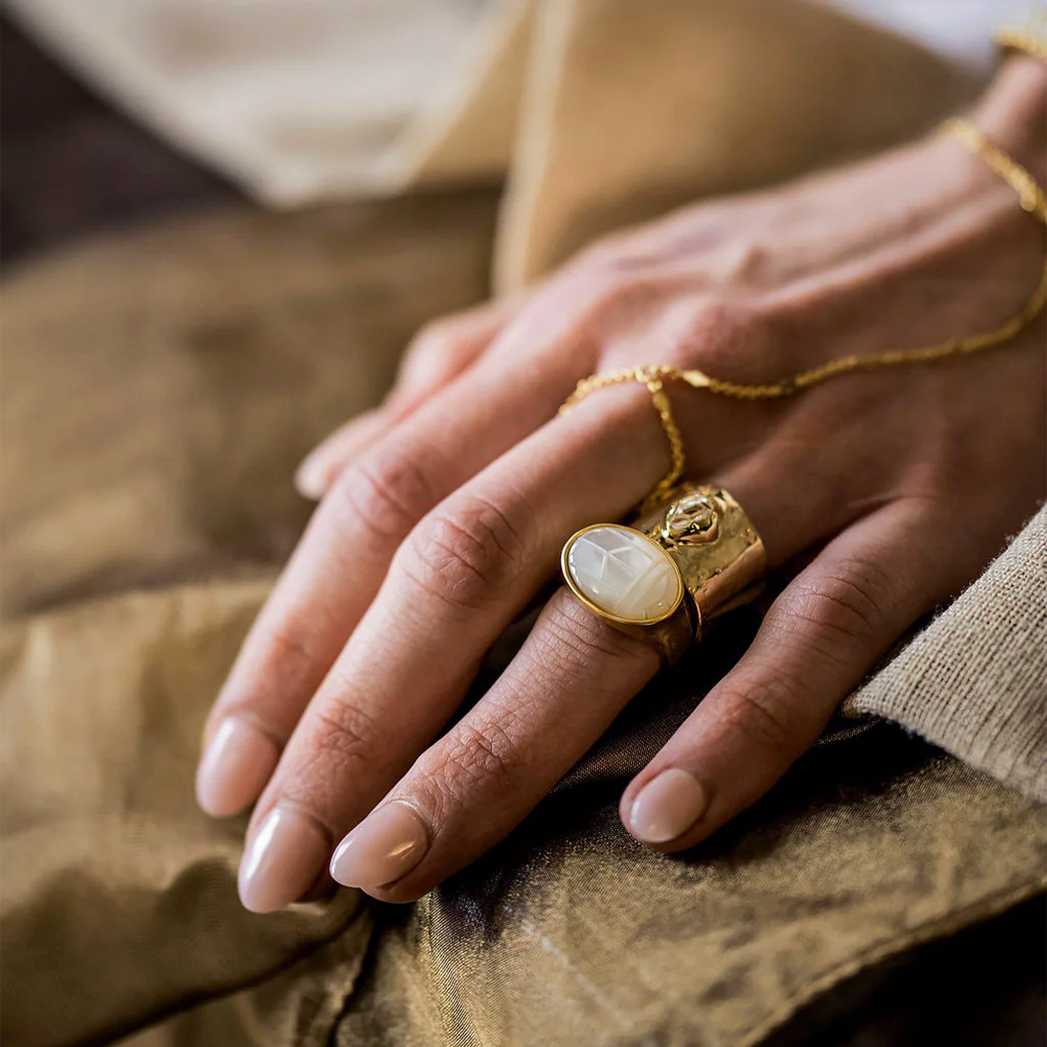 A gold oval mother of pearl stone sitting in a gold plated setting. 