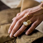 A gold oval mother of pearl stone sitting in a gold plated setting. 