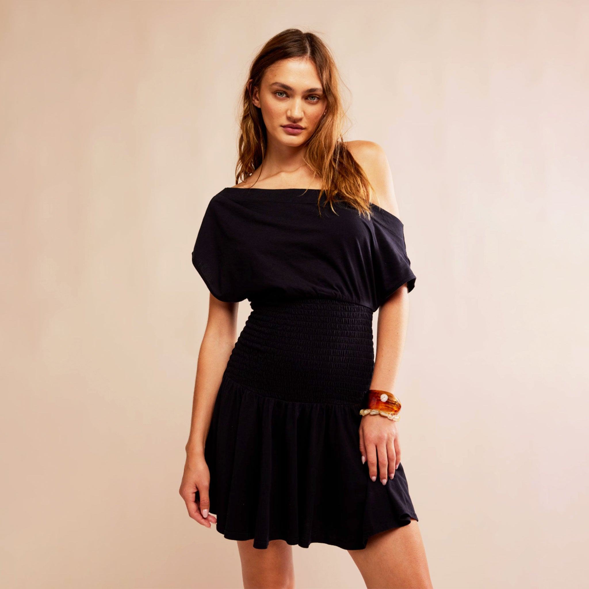 A black mini dress with a slouchy off the shoulder neckline and a flowy skirt lower half.