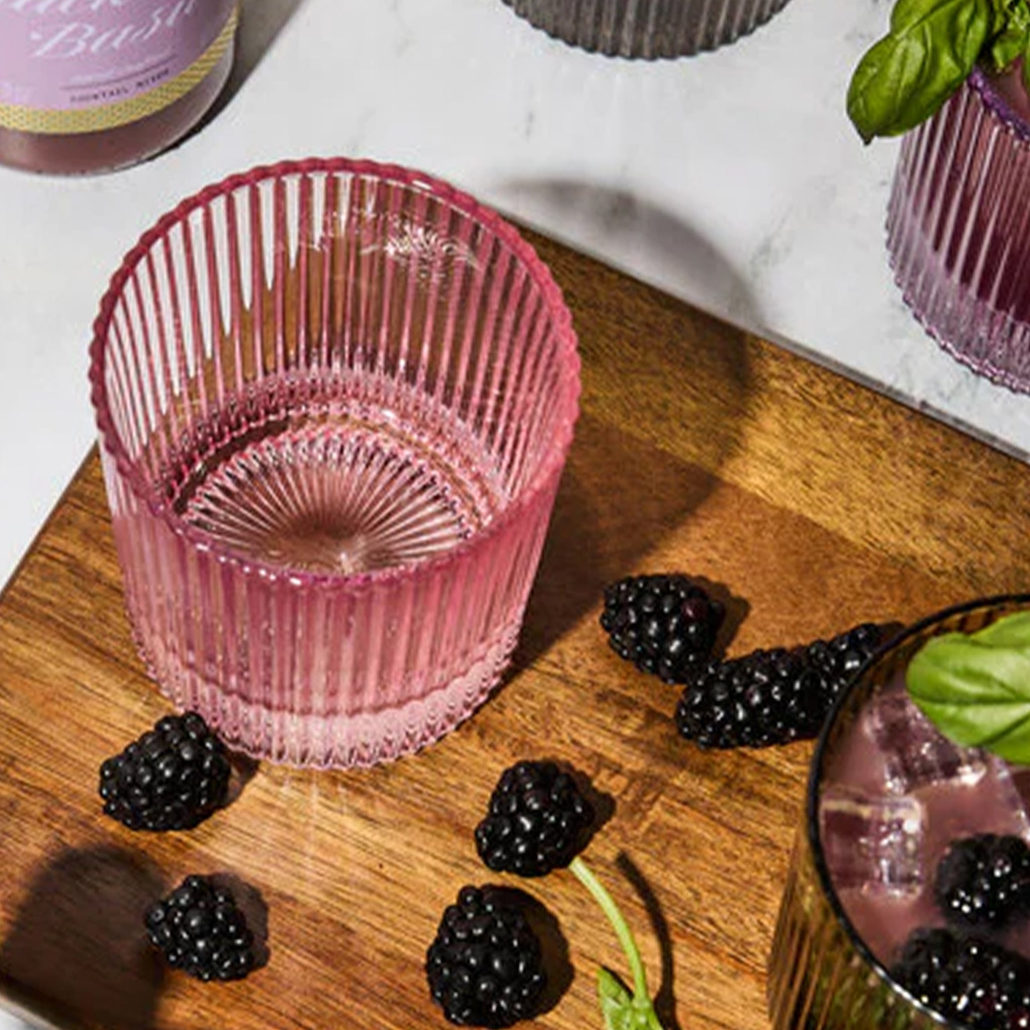 A set of pink ribbed lowball cocktail glasses. 