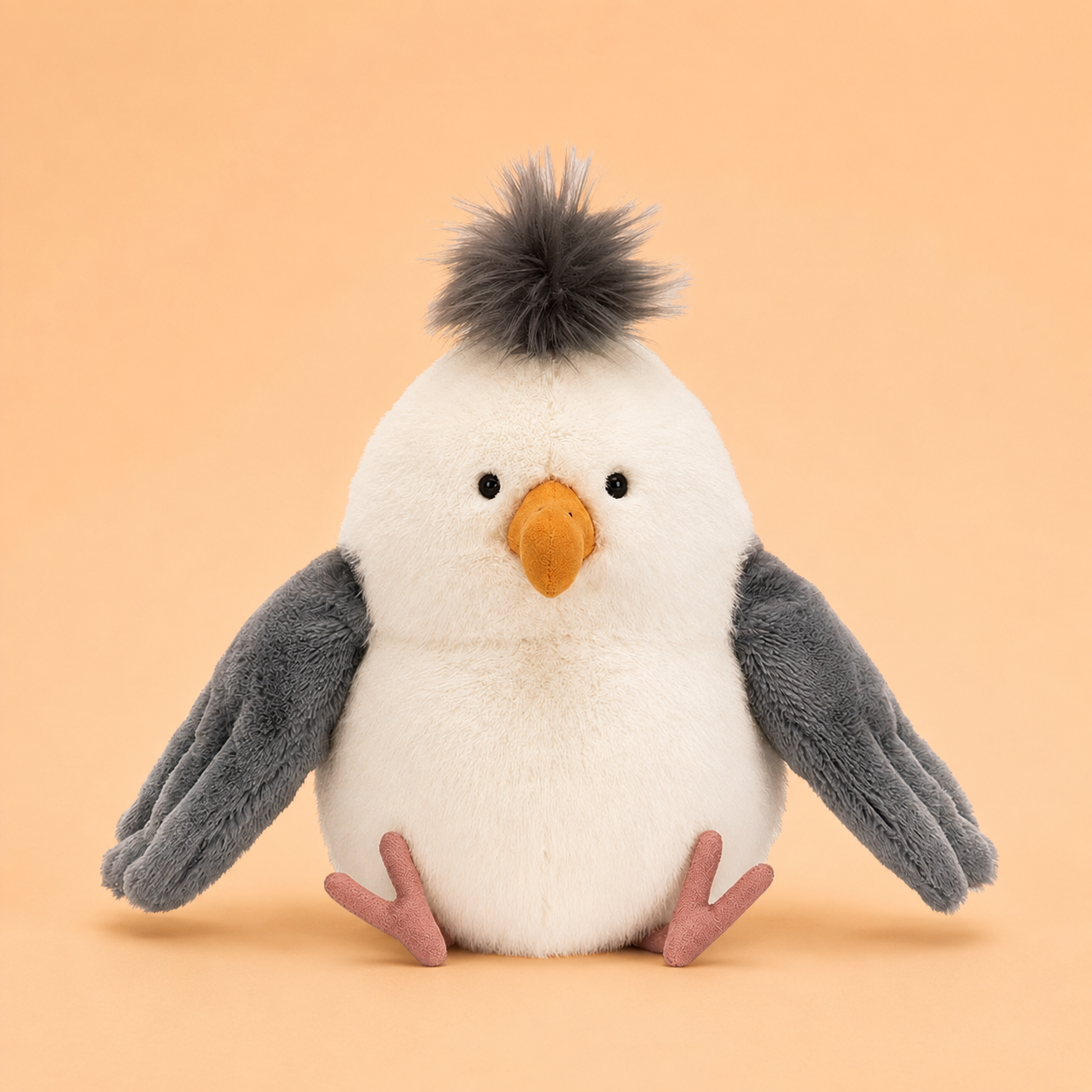 On a tan background is a seagull stuffed animal toy.