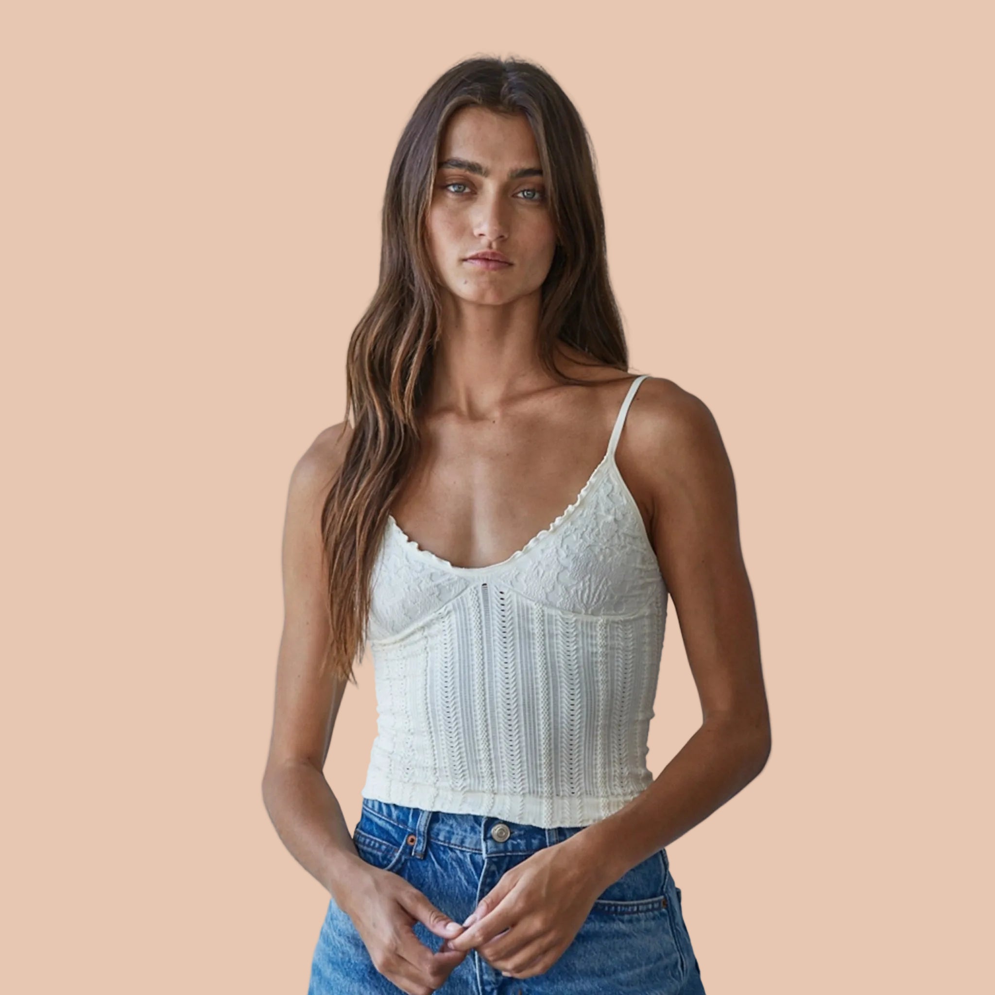 A cream colored white tank top with a textured print and thin spaghetti straps. 