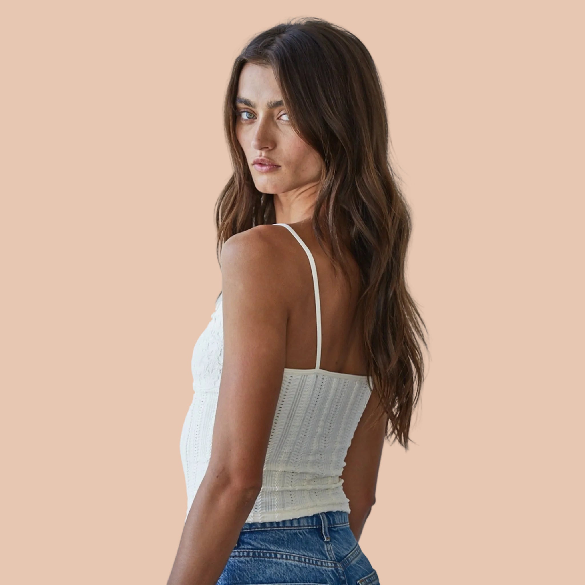 A cream colored white tank top with a textured print and thin spaghetti straps. 