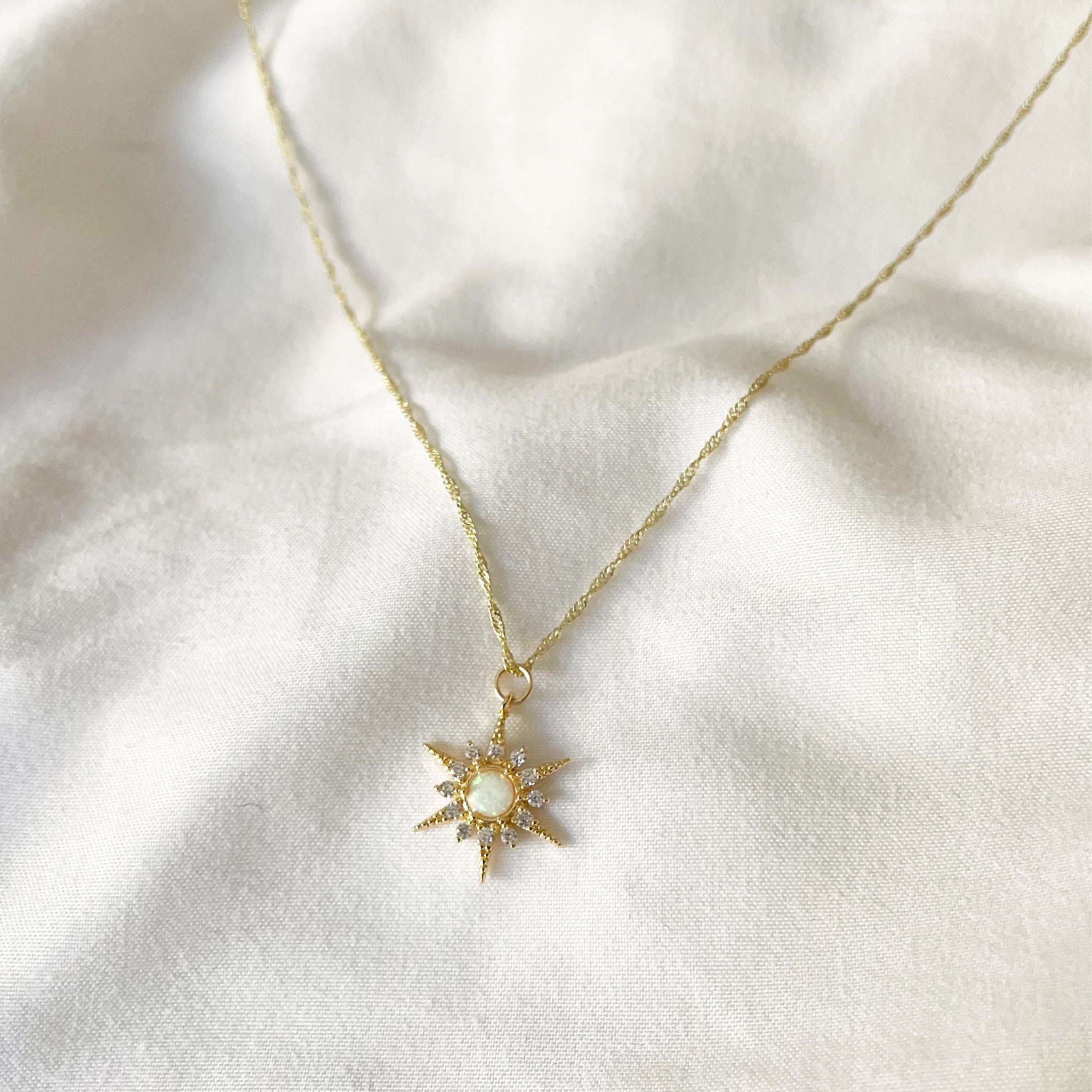 Gold necklace with a star-shaped pendant on a white fabric background