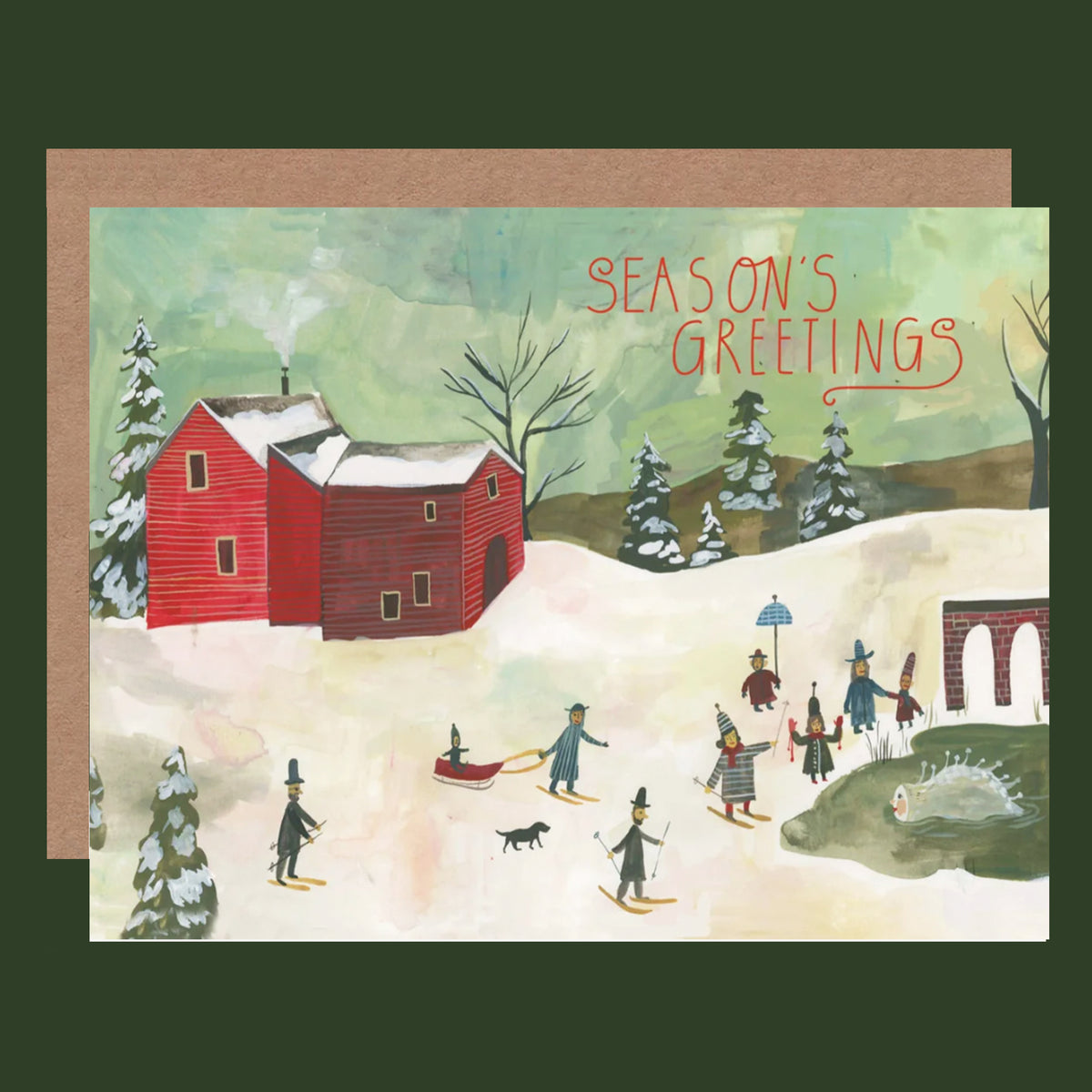 A winter-themed greeting card with a kraft envelope, featuring a hand-painted style illustration of people skiing in a snowy landscape with a red barn and the text 'SEASON'S GREETINGS'.