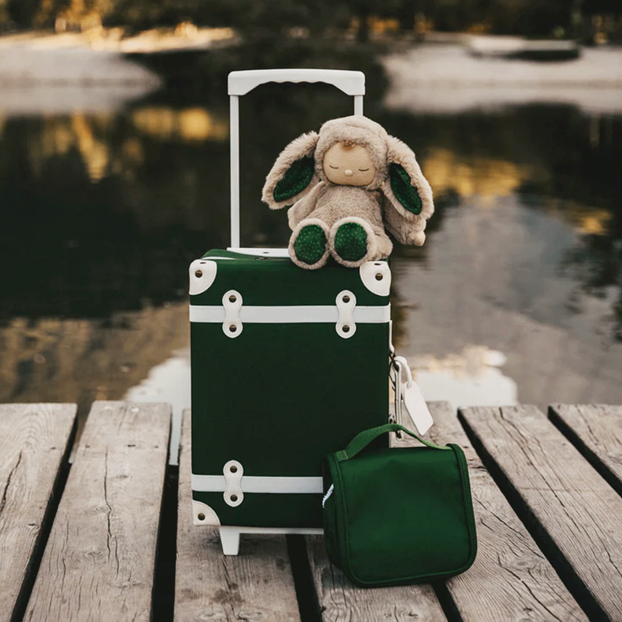 A dark green children&#39;s suitcase with white details. 