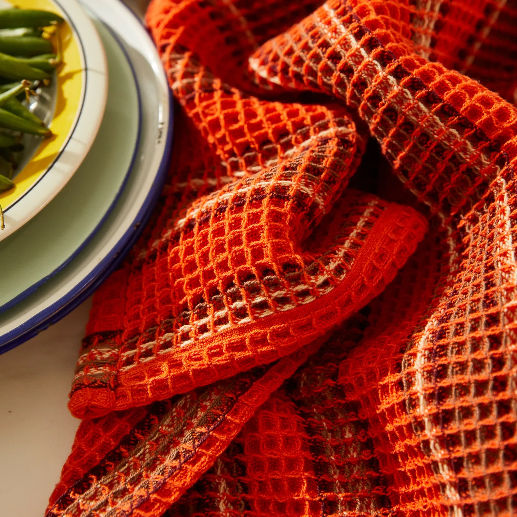 An orange and brown striped waffle knit tea towel. 