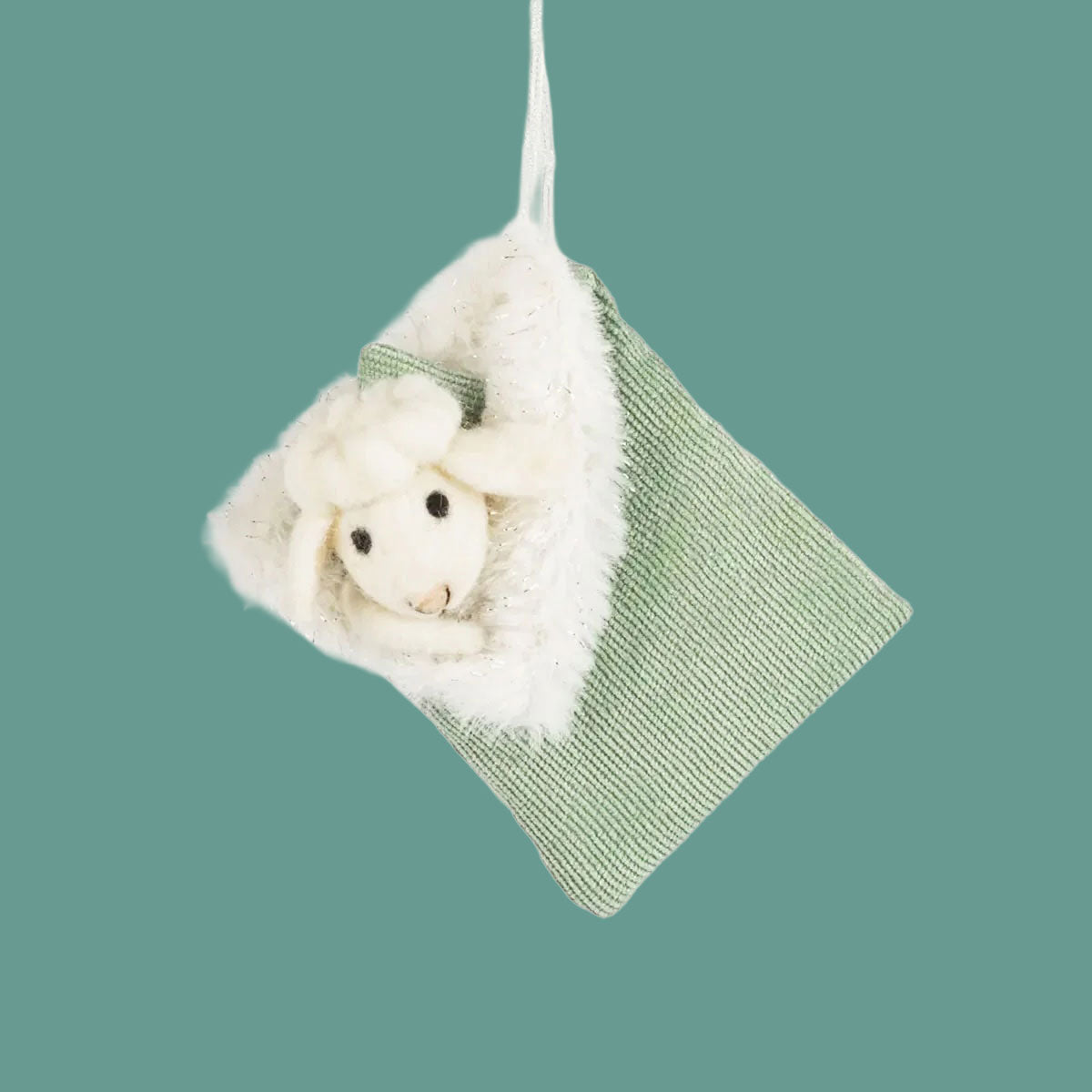 A sheep and sleeping bag shaped green ornament made of wool and felt with a string loop for hanging. 