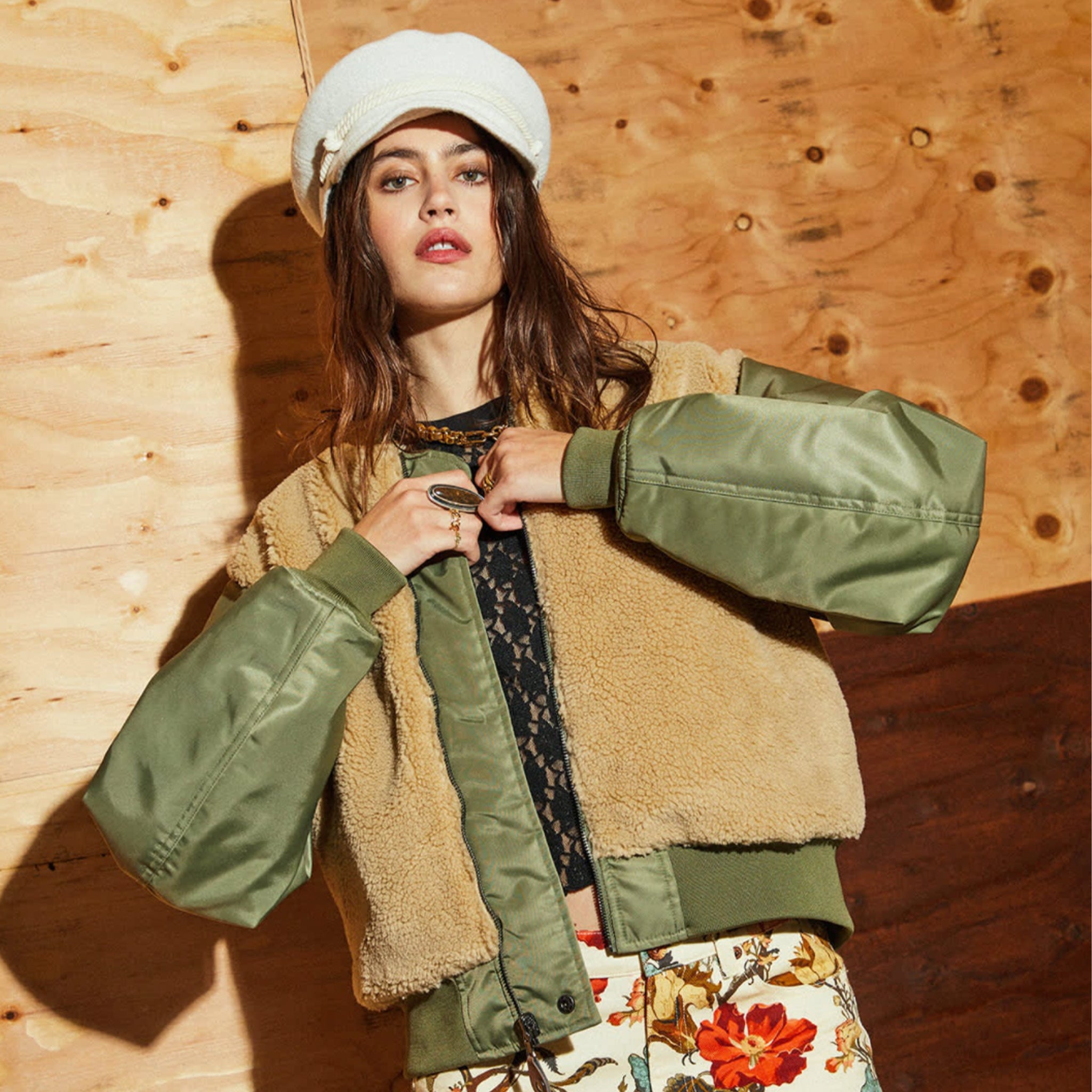 A green olive bomber jacket with a tan sherpa lining on the body and back of the jacket. 