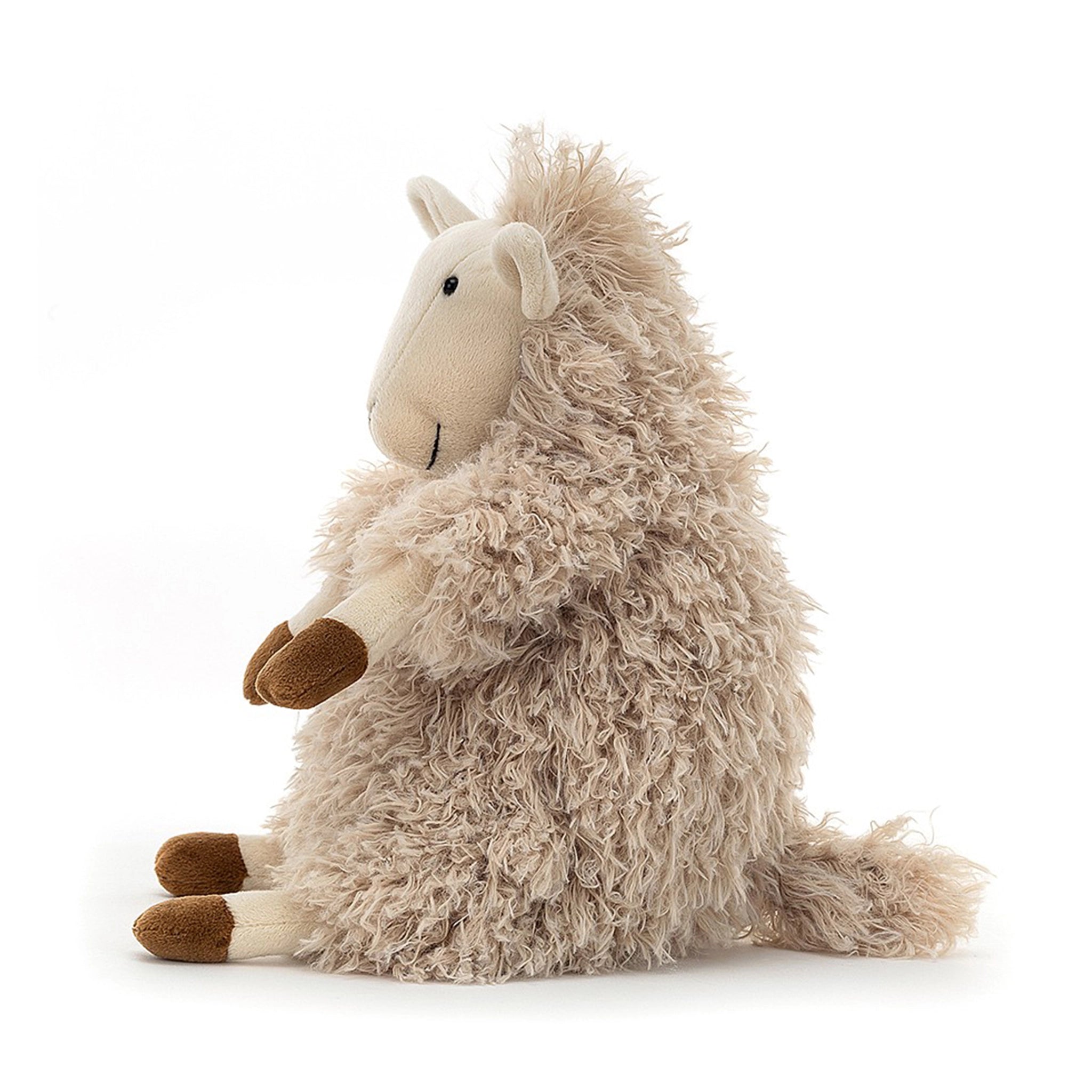 On a white background is a neutral tan stuffed animal sheep with fluffy fur. This photo is of the side profile of the sheep. 