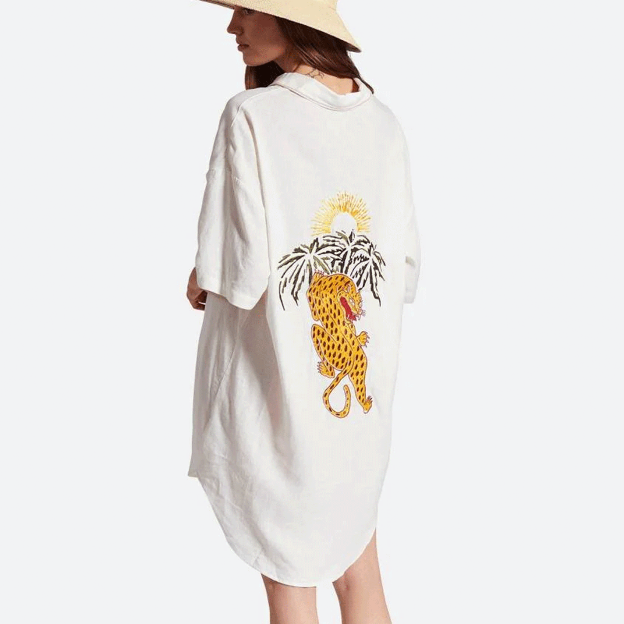 On a white background is a button up shirt dress with short sleeves and a jaguar and palm tree graphic on the back.