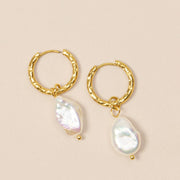 A pair of gold hoop earrings with a pearl bead off the bottom.
