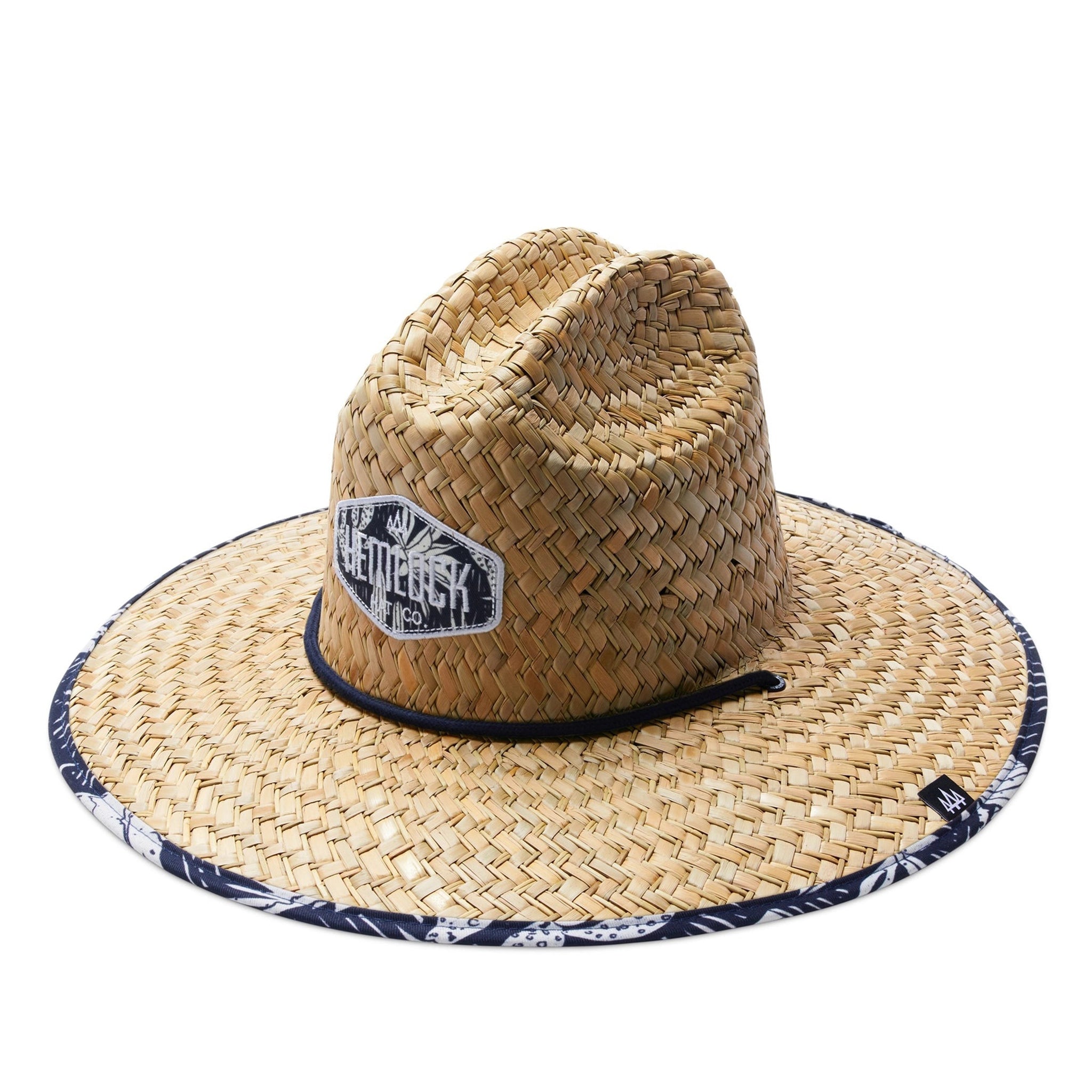 A straw sun hat with a dark blue and white desert design under the brim and a coordinating neck strap.
