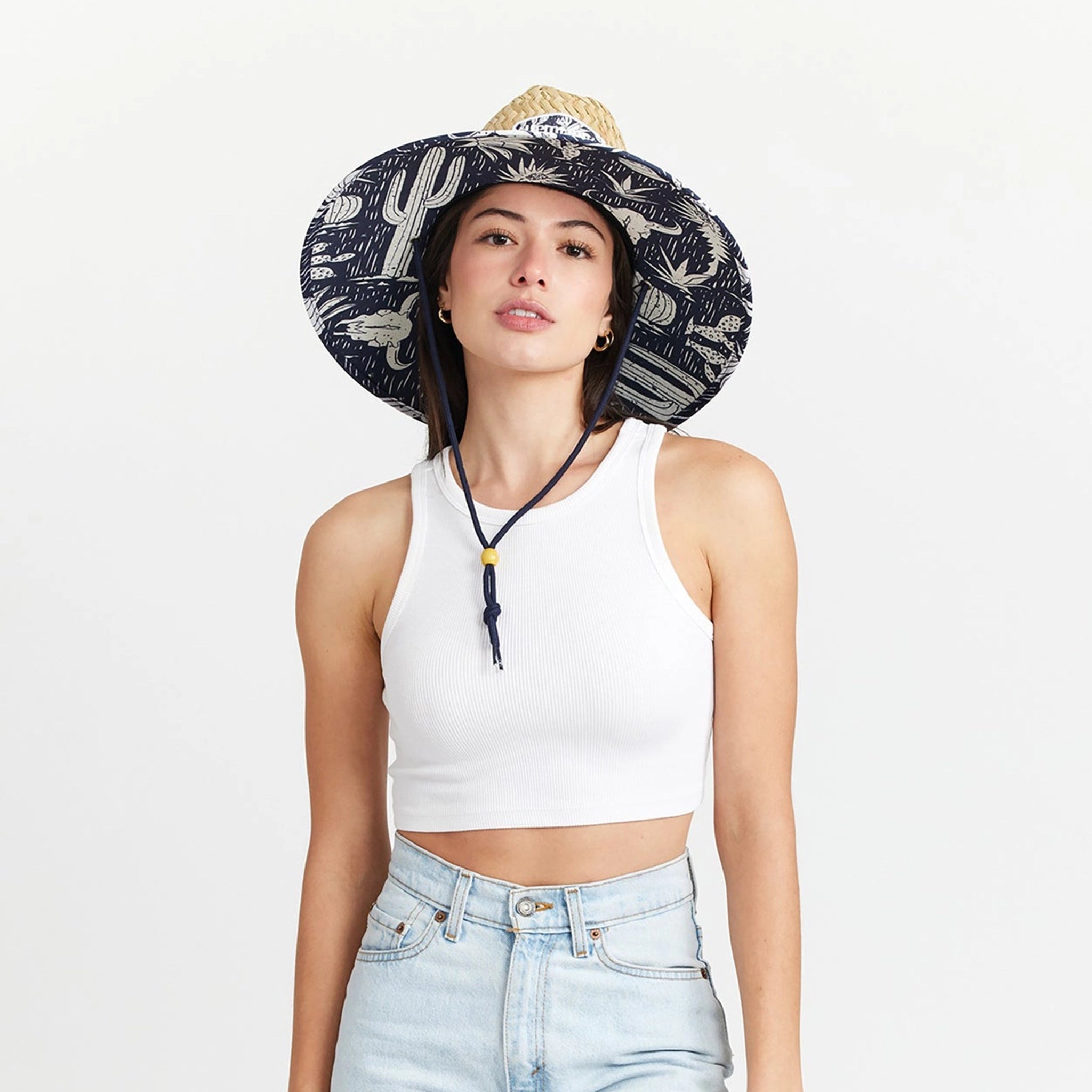 A straw sun hat with a dark blue and white desert design under the brim and a coordinating neck strap.