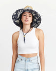 A straw sun hat with a dark blue and white desert design under the brim and a coordinating neck strap.
