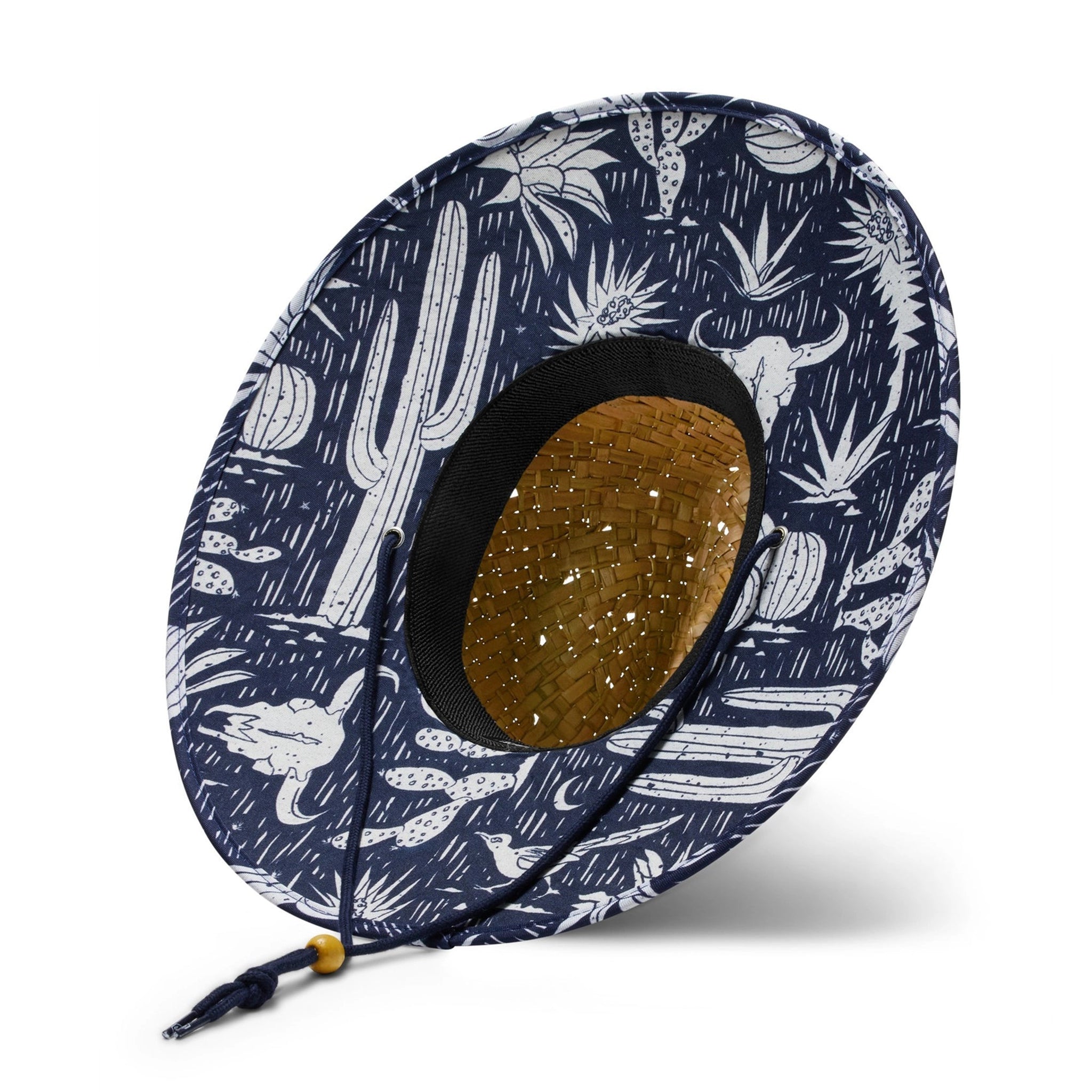 A straw sun hat with a dark blue and white desert design under the brim and a coordinating neck strap.
