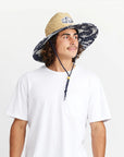 A straw sun hat with a dark blue and white desert design under the brim and a coordinating neck strap. 