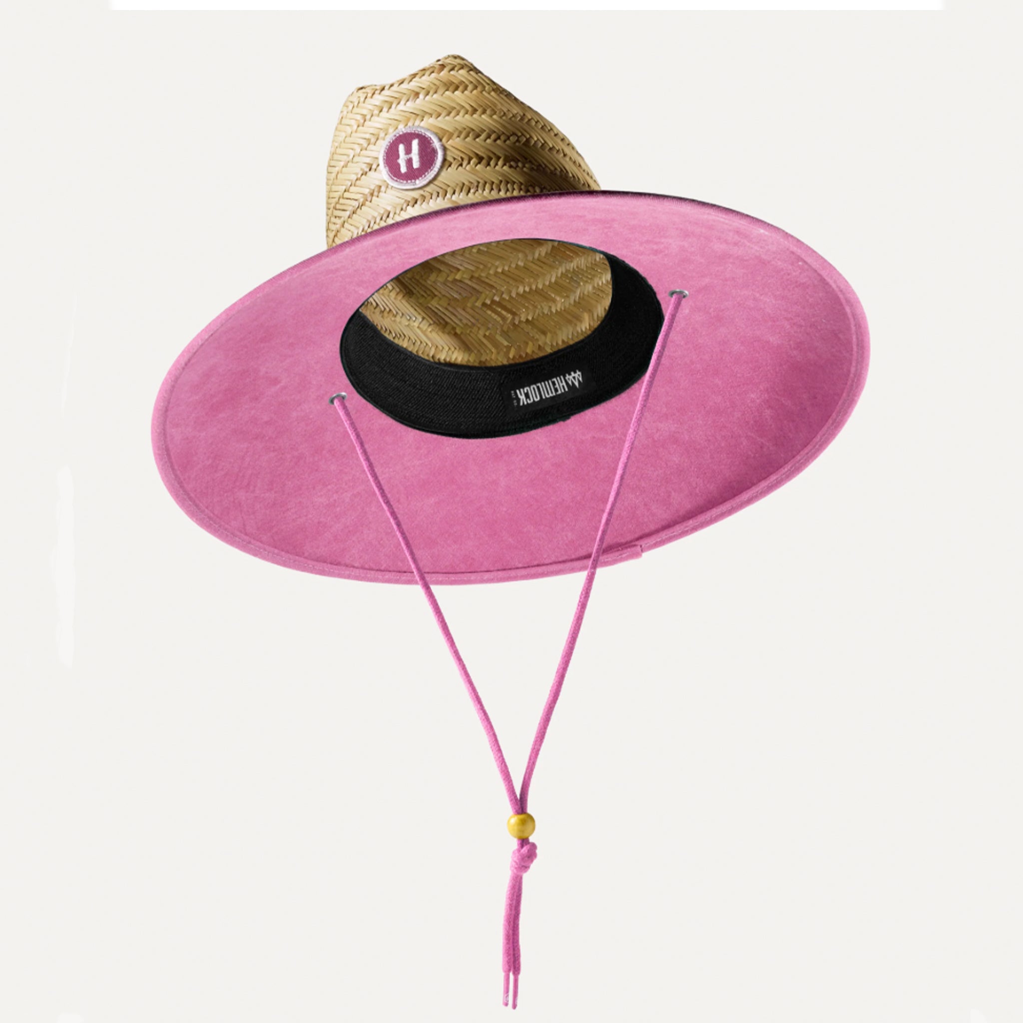 A tan and solid pink straw sun hat with a string necktie. 