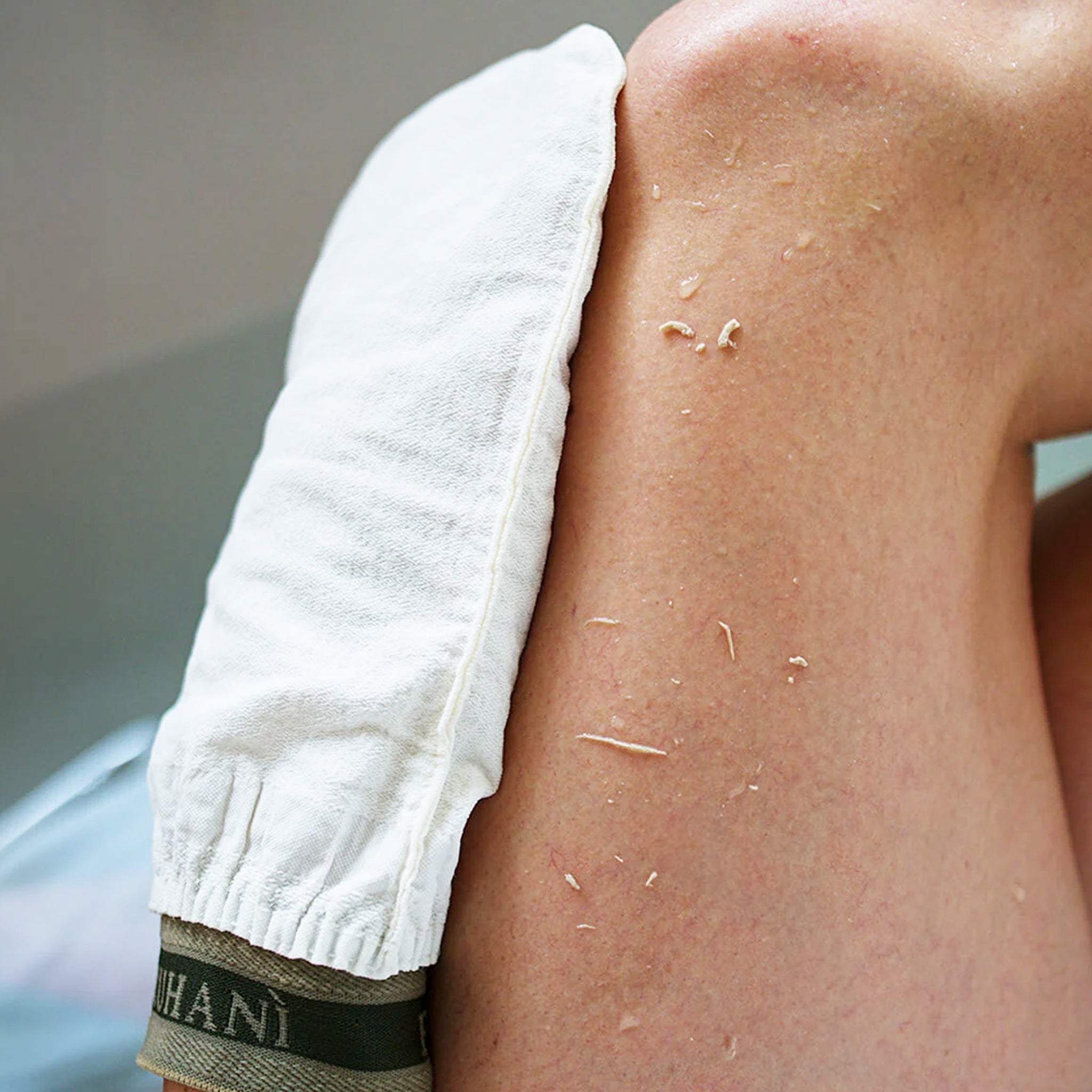 A photo of the exfoliating glove on a model&#39;s leg showing the dead skin and exfoliation it&#39;s able to produce. 