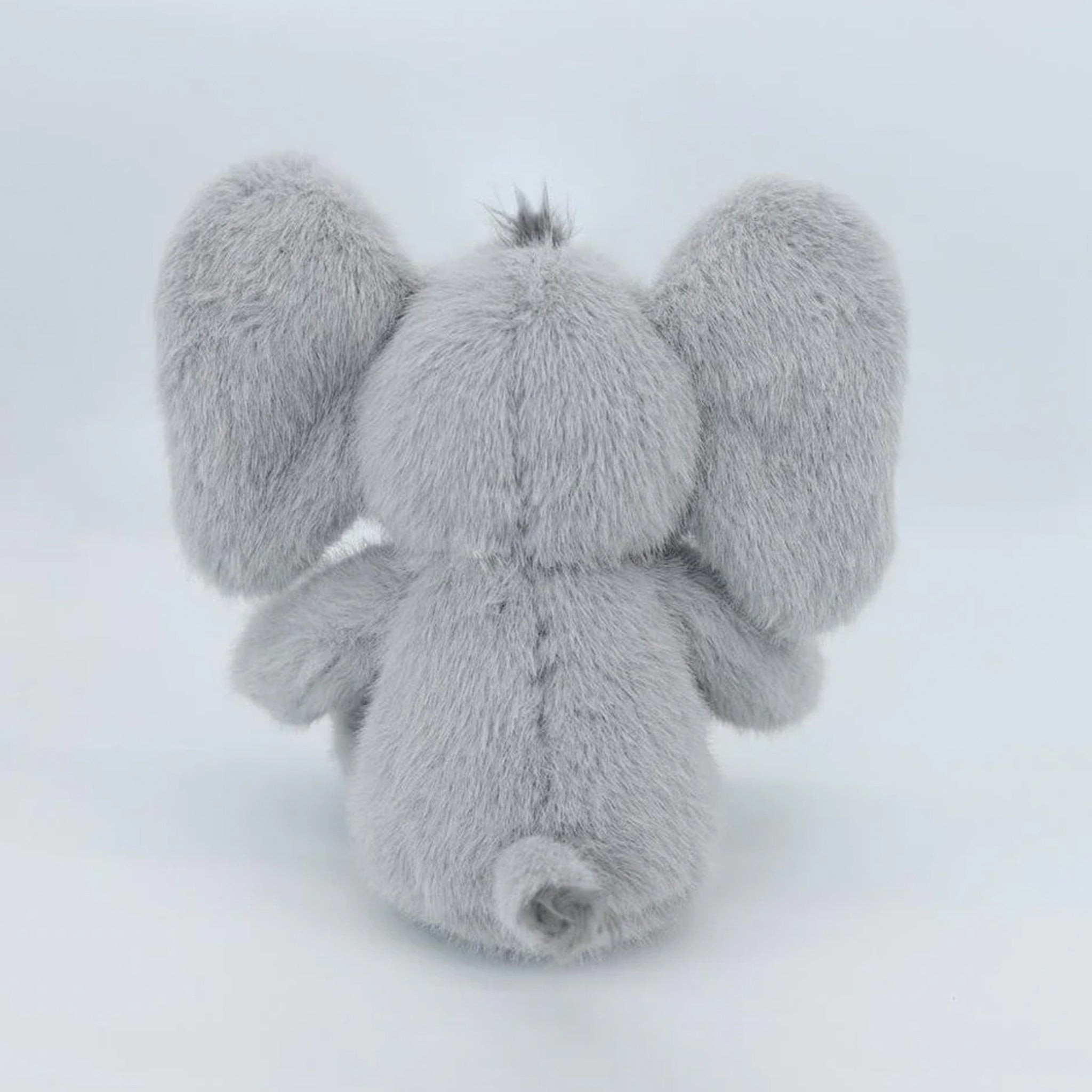 A grey baby elephant shaped stuffed animal. 